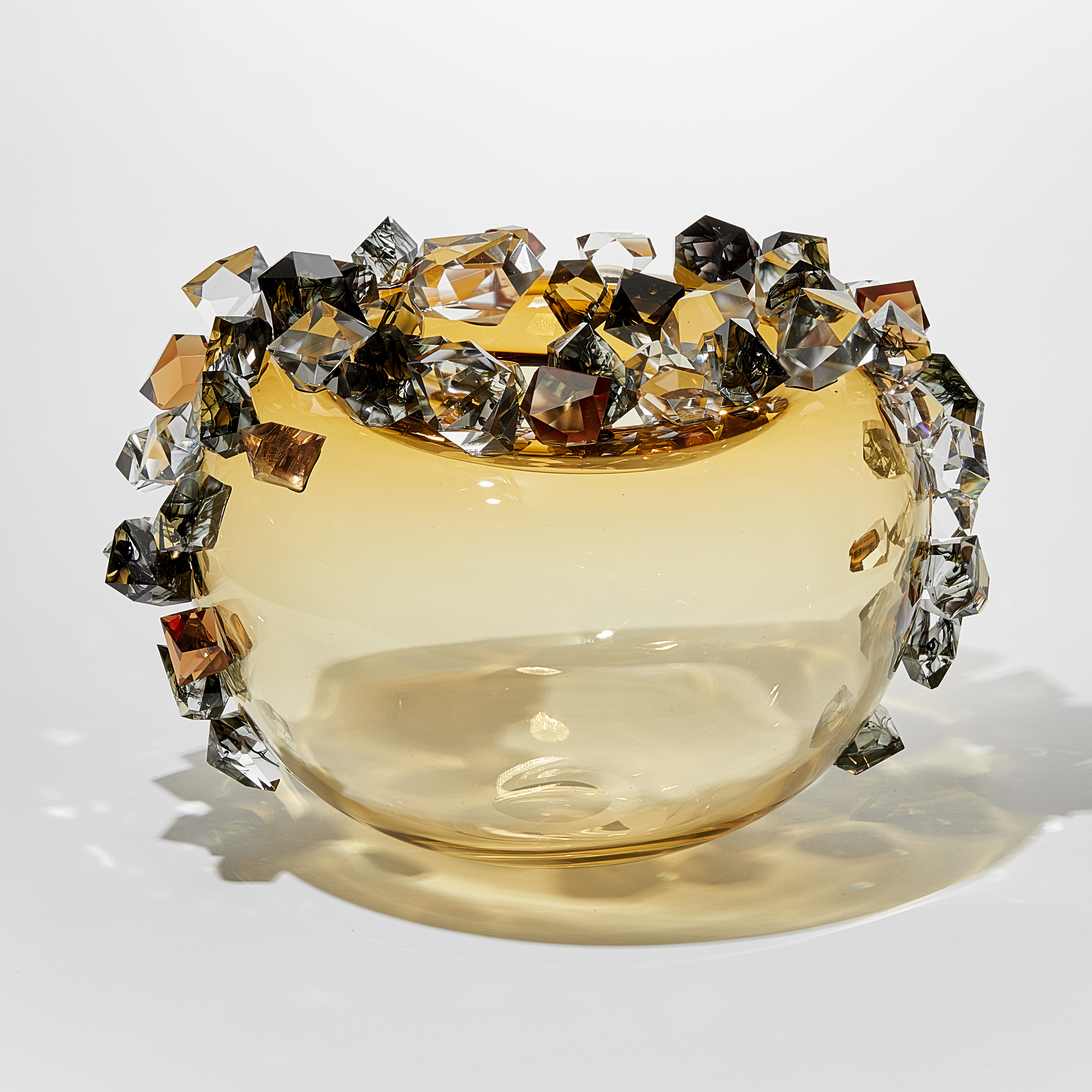 round light amber gold round transparent bubble covered in oversized irregular shaped gem stones in amber grey and clear with some with inky swirls trapped within handmade from glass
