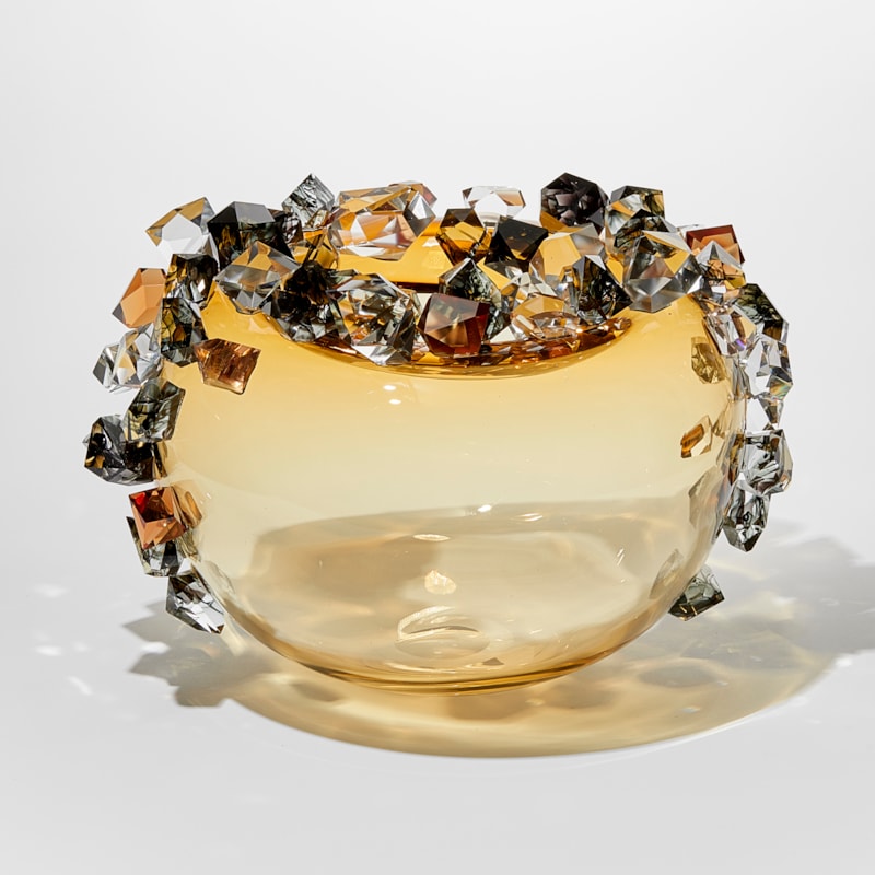 round light amber gold round transparent bubble covered in oversized irregular shaped gem stones in amber grey and clear with some with inky swirls trapped within handmade from glass