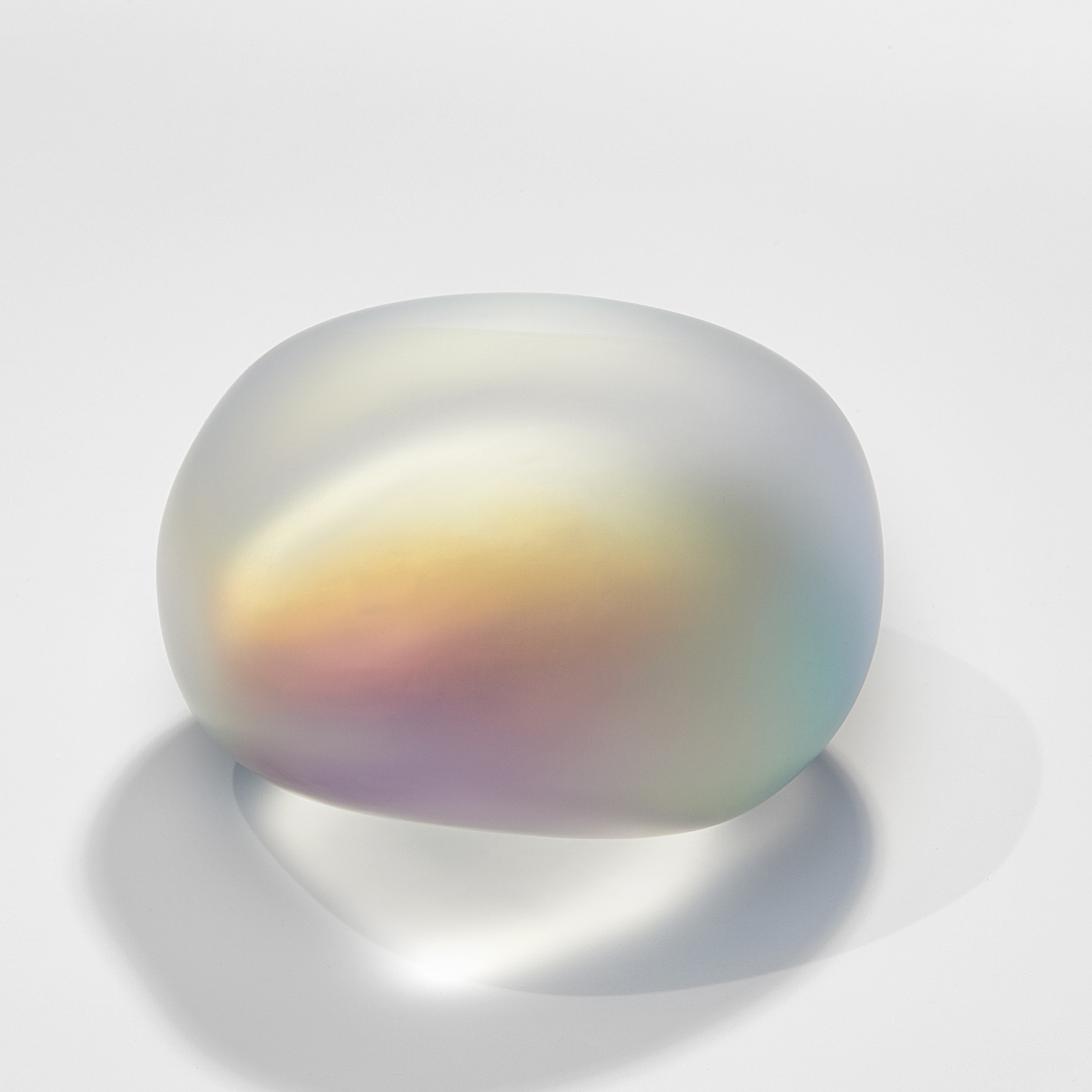 smooth amorphic glass pebble and rock inspired sculpture in matt clear glass with inner myriad of colours bursting from within as if there is a trapped shimmering mother of pearl light inside