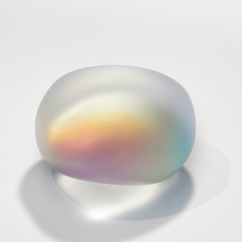 smooth amorphic glass pebble and rock inspired sculpture in matt clear glass with inner myriad of colours bursting from within as if there is a trapped shimmering mother of pearl light inside