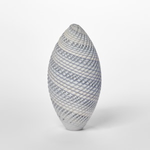 pointed standing ovoid shaped vessel with banded coloured and cut lines in white cream blue and grey twisting round the from hand made from glass