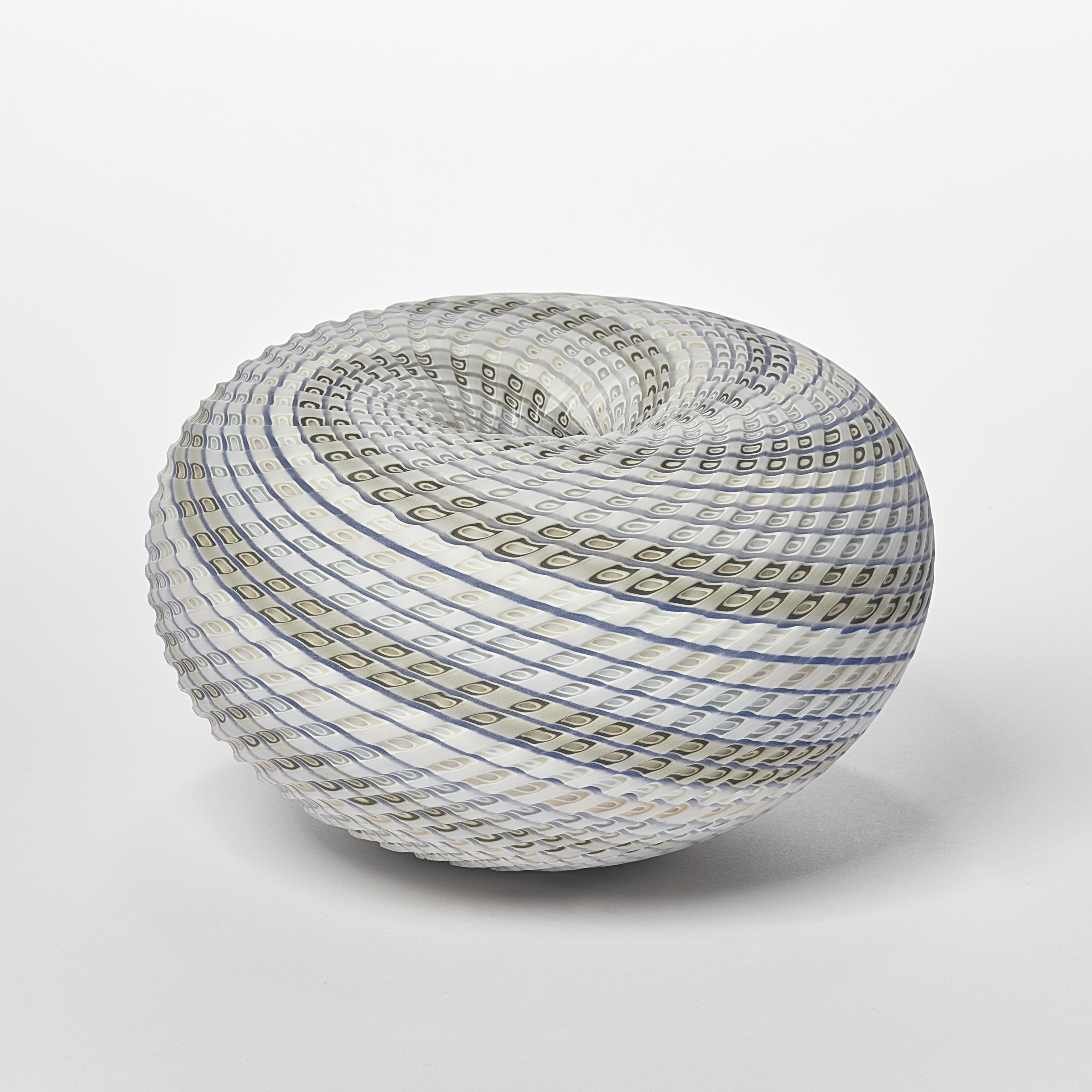 round vessel in soft blue off white blue and green with swirling lines to the dipped vortex centre with lines both coloured and cut within the surface handmade from glass