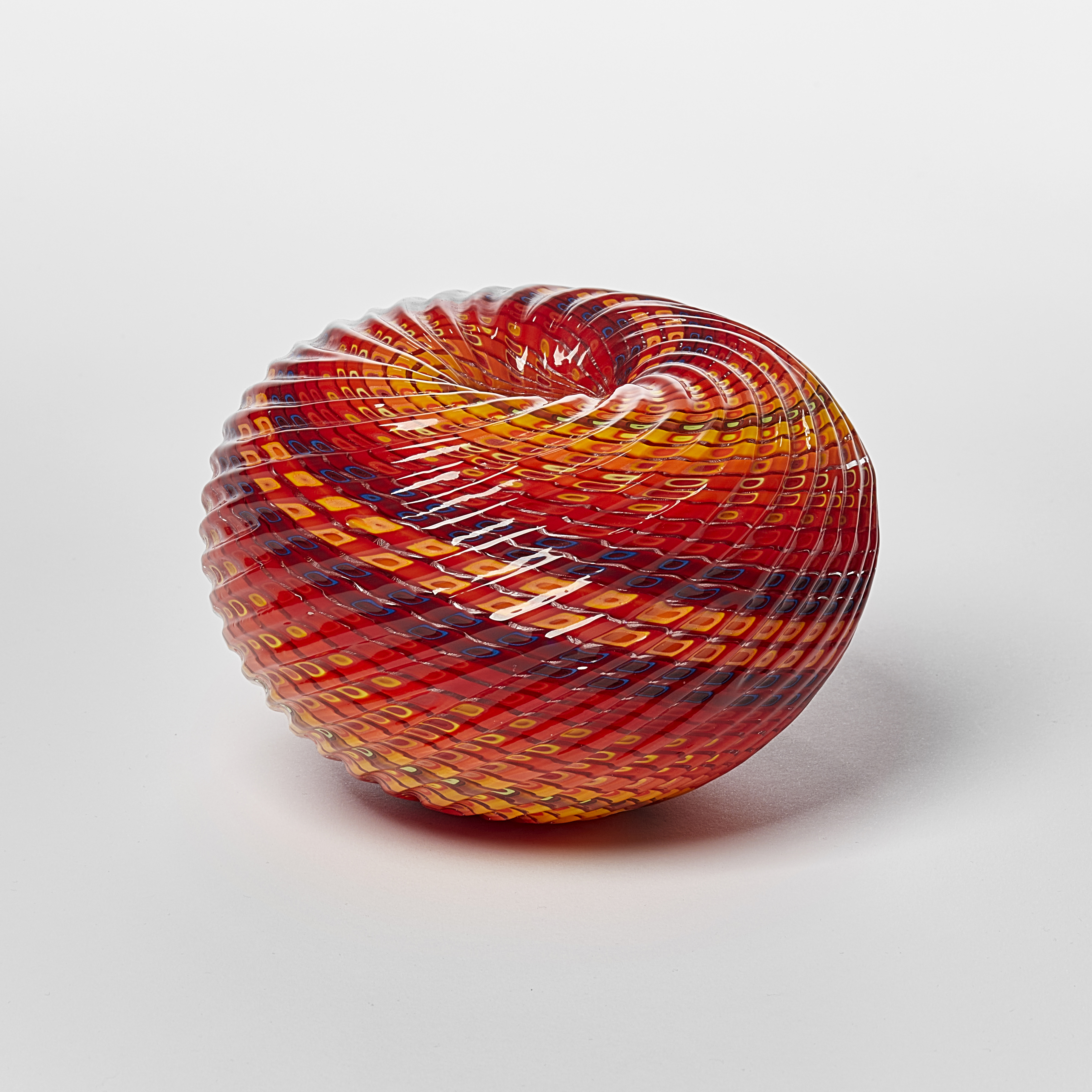 round textured orange yellow and aubergine purple striped vessel with central dipped opening with straight cut recessed lines swirling around the piece hand made from glass