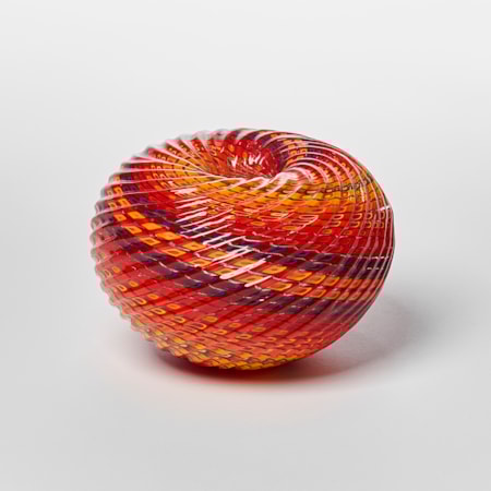 round textured orange yellow and aubergine purple striped vessel with central dipped opening with straight cut recessed lines swirling around the piece hand made from glass