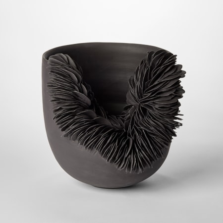 round black bowl with front side cut away and filled with stacked black rocky shards hand thrown from coloured porcelain