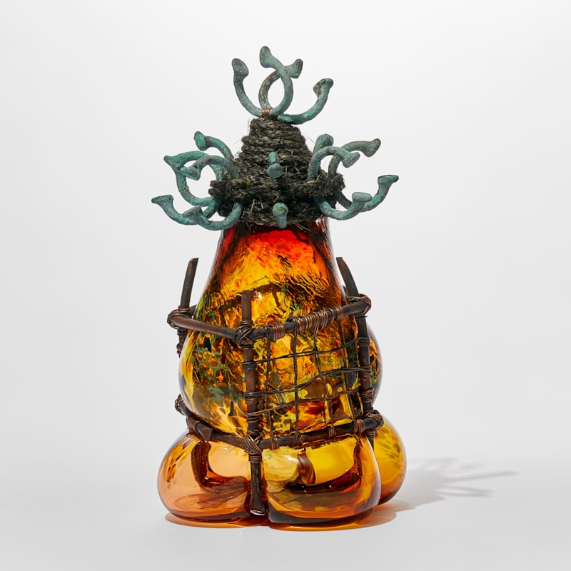 hand made transparent textured red and amber amorphic glass sculpture trapped within a square copper pipe and wire cage with bound rope top interlaced with copper manillas