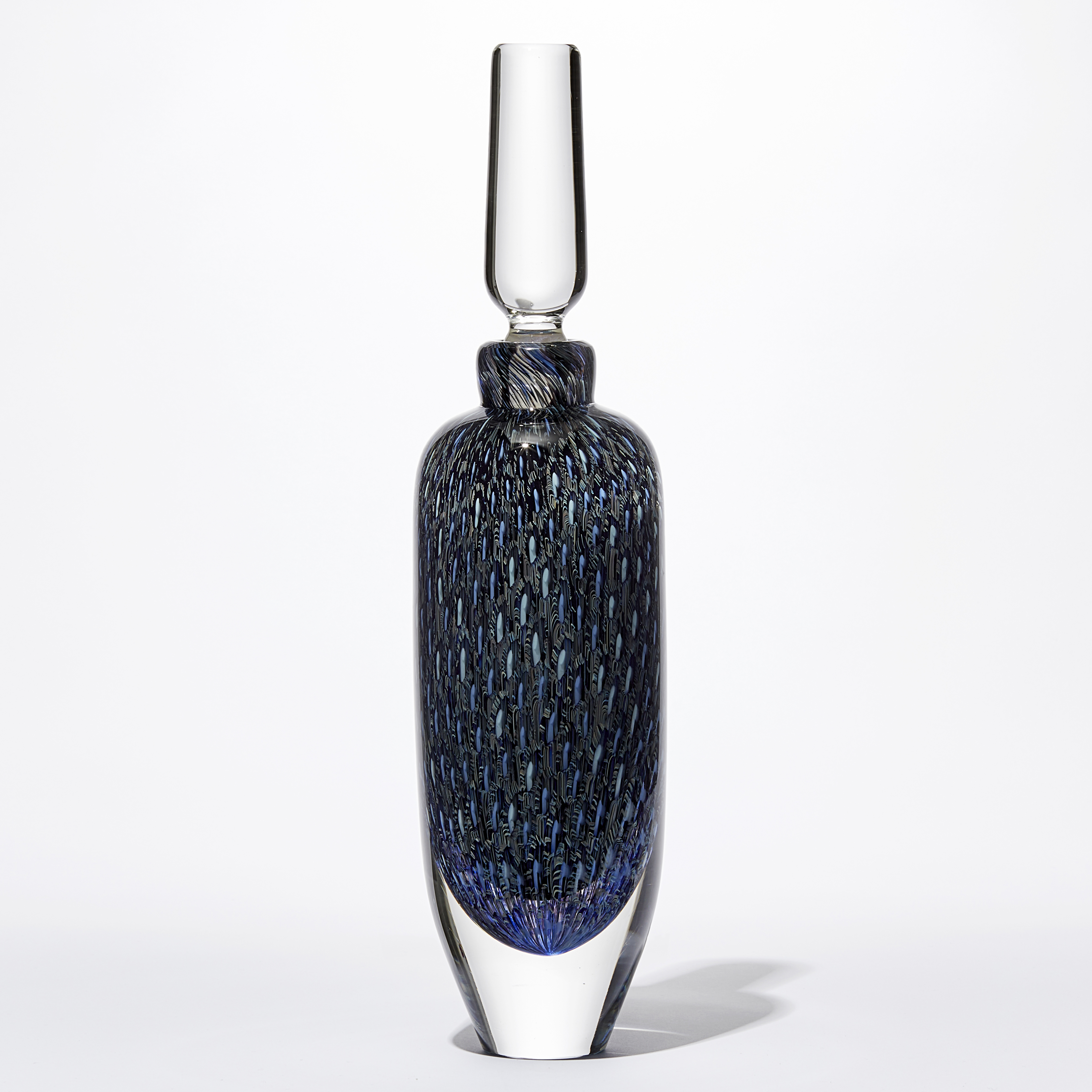 tall rounded transparent bottle with long elegant clear stopper with the main body covered in an fine intense organic repeat pattern in blue indigo turquoise jade and aquamarine hand made from glass 
