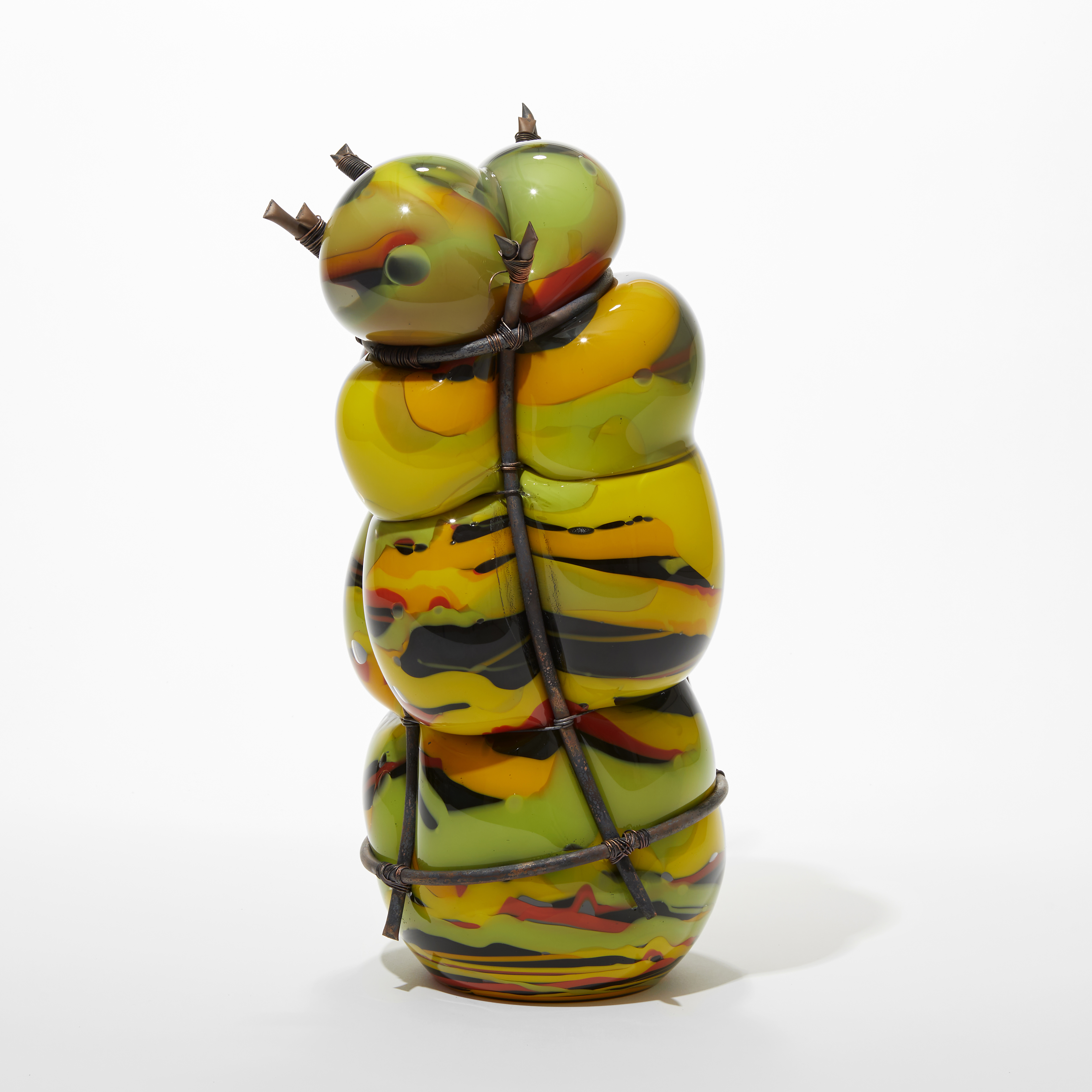 hand made  and blown lime green orange red and black organically banded standing  glass sculpture held within a copper cage and bulging between the gaps