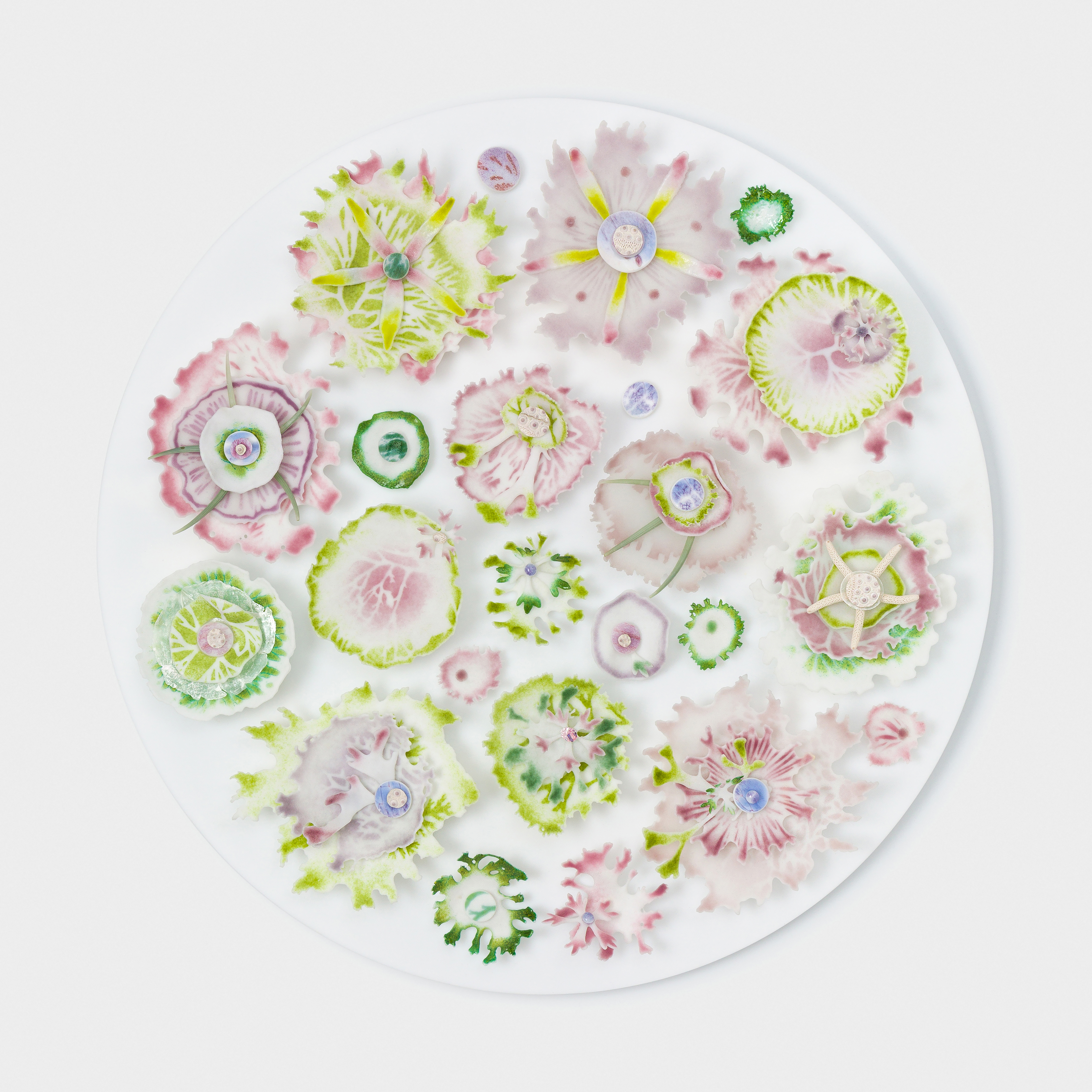 flat white round vertical opaque disc covered in organic abstract finely detailed floral and coral reef inspired relief adornments in pink aubergine lime green and dark apple green hand made from glass