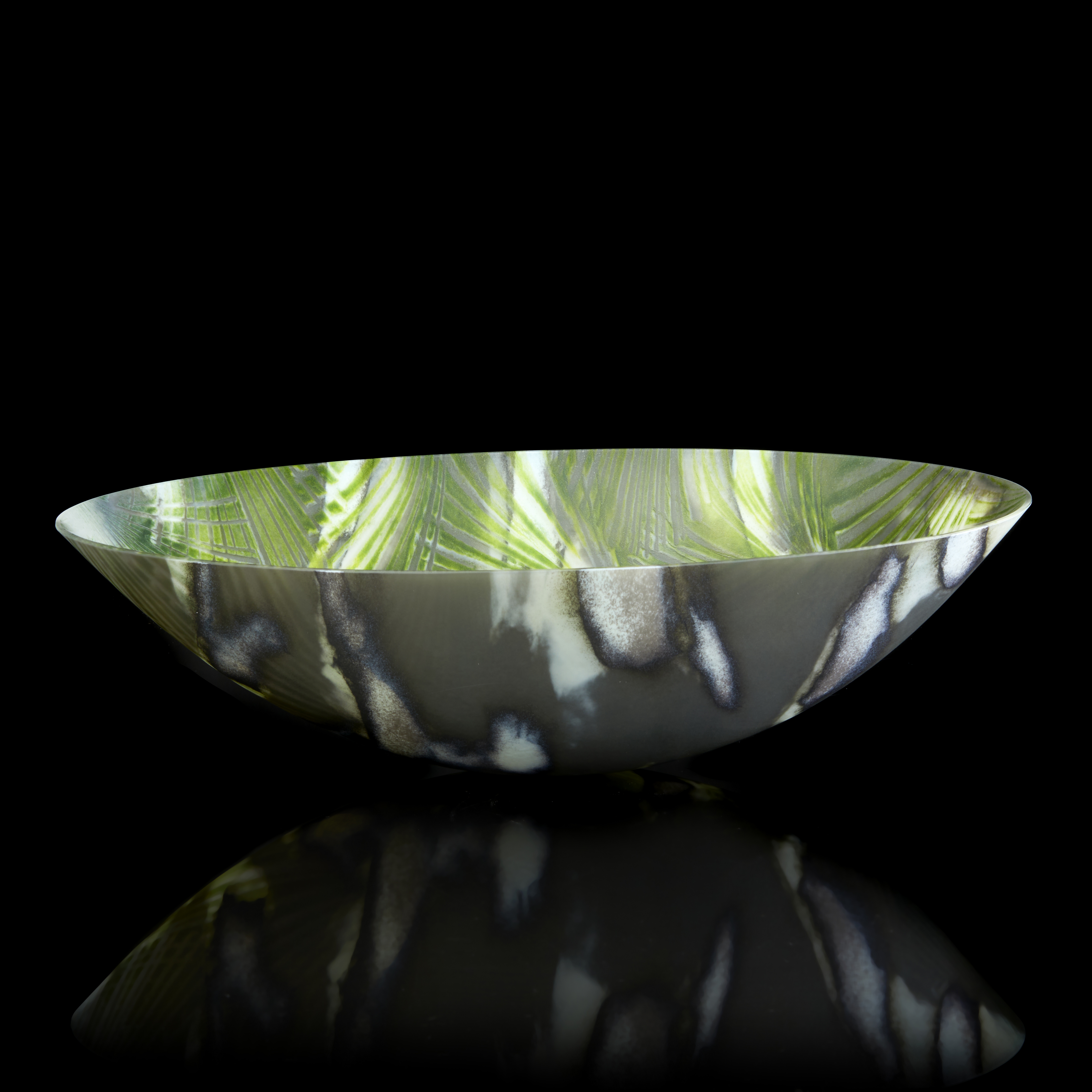 oval bowl with sweeping sides and rounded base with palm tree interior repeat pattern and exterior camouflage pattern in a myriad of greens hand made from glass