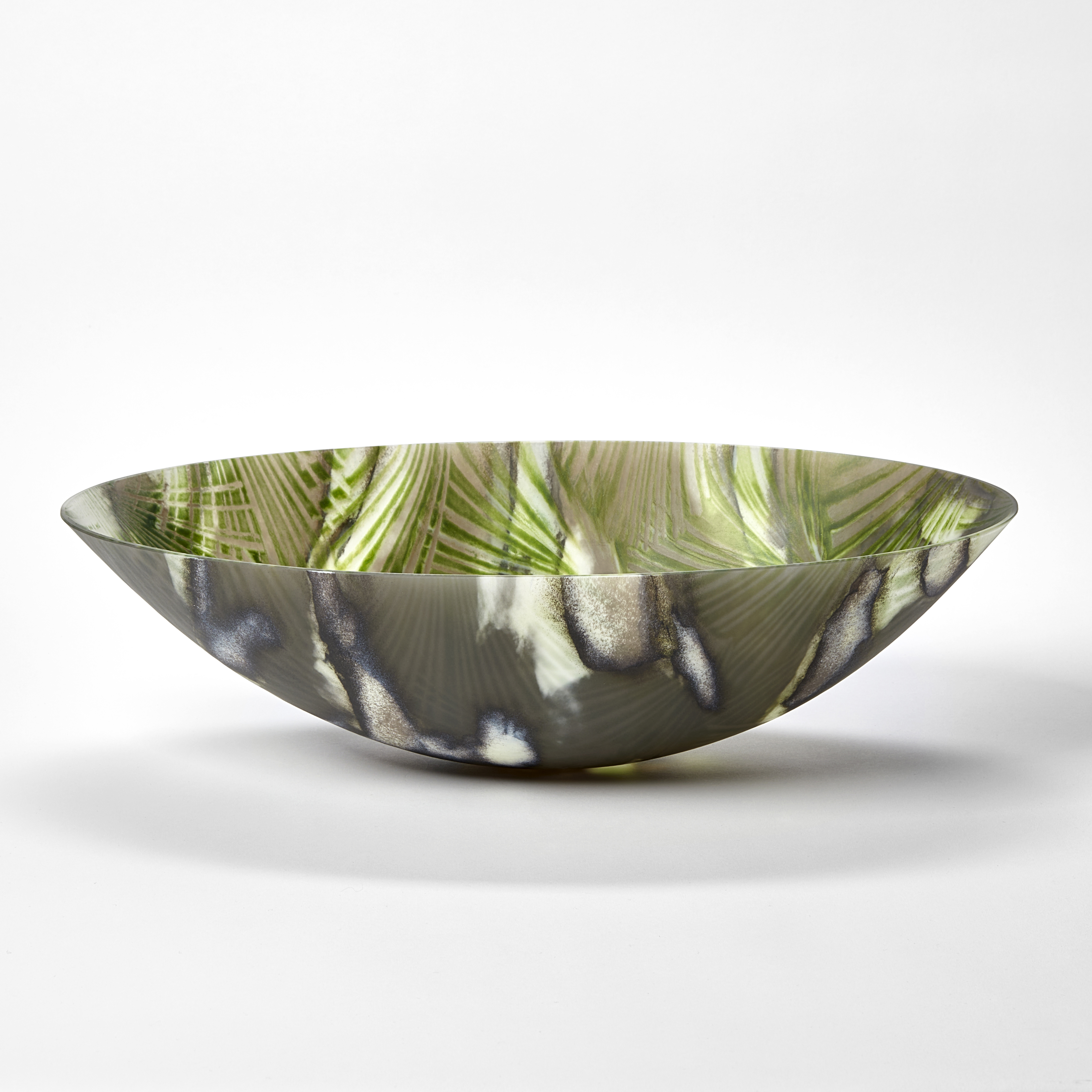 oval bowl with sweeping sides and rounded base with palm tree interior repeat pattern and exterior camouflage pattern in a myriad of greens hand made from glass