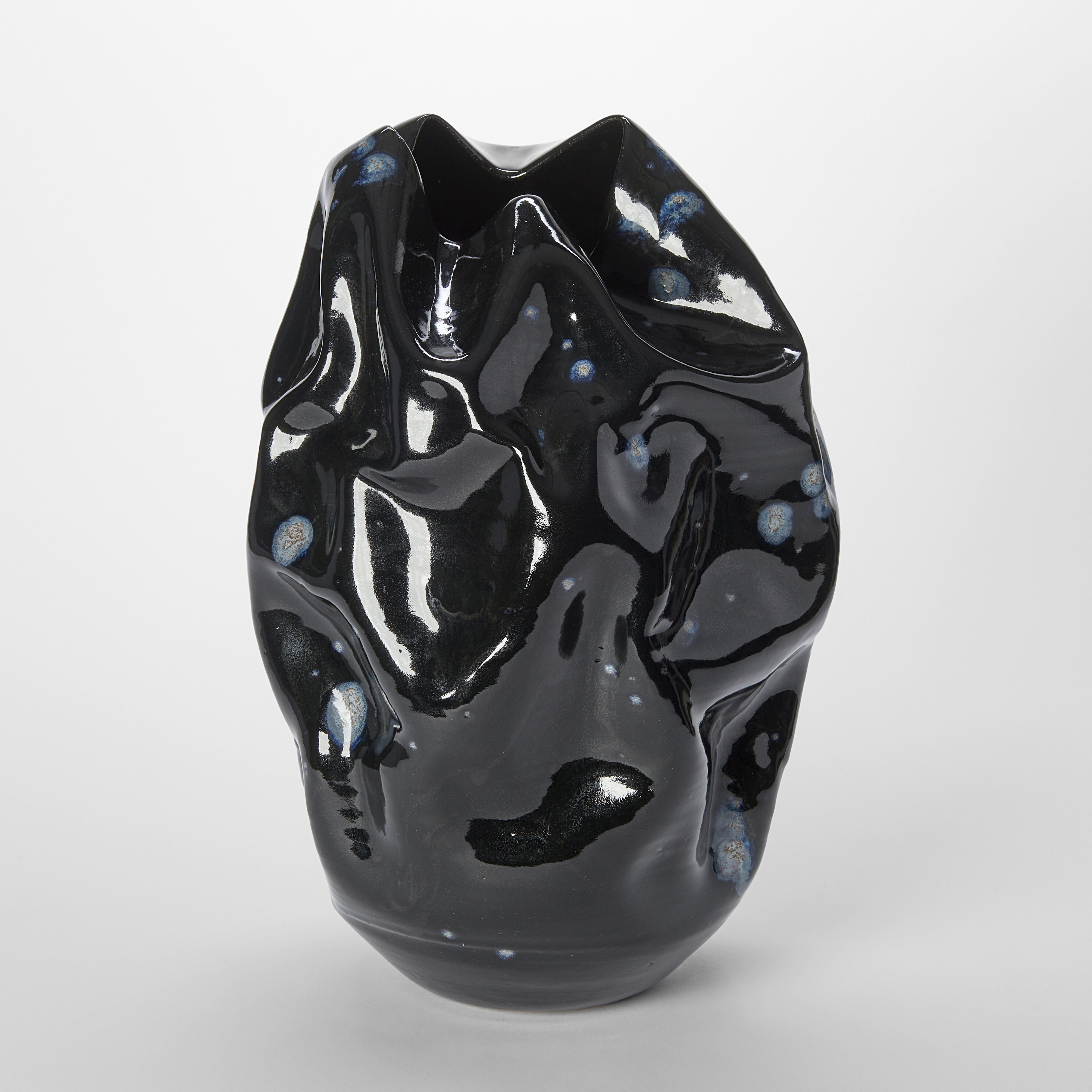 crumpled wrinkled and undulating vessel with glossy black surface with blue ink blot irregular details hand made from ceramics