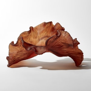 rich dark burnt orange amber organic arched frilled sculpture with the appearance of sea adrift seaweed with one smooth side and one slightly ridged hand made from glass