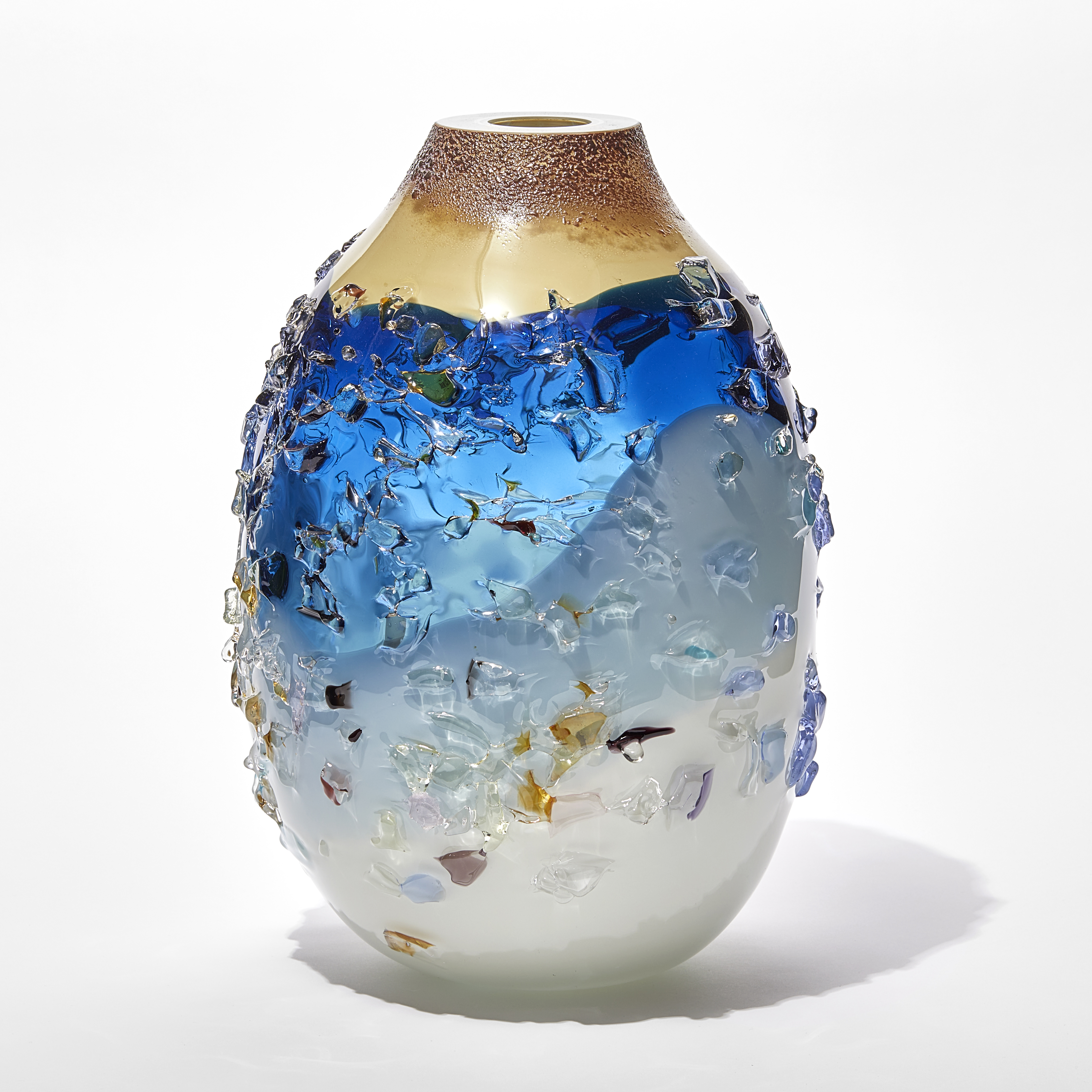 oval vase with milky white base fading to a turquoise banded middle with transparent blue upper topped with an opaque Cappuccino coloured top with the entire surface covered in multicoloured shards hand made from glass