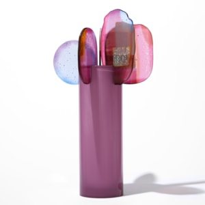 opaque raspberry pink cylinder with five rounded finals with abstract patterns in pink blue purple and gold perched on the top edge hand made from blown and fused glass