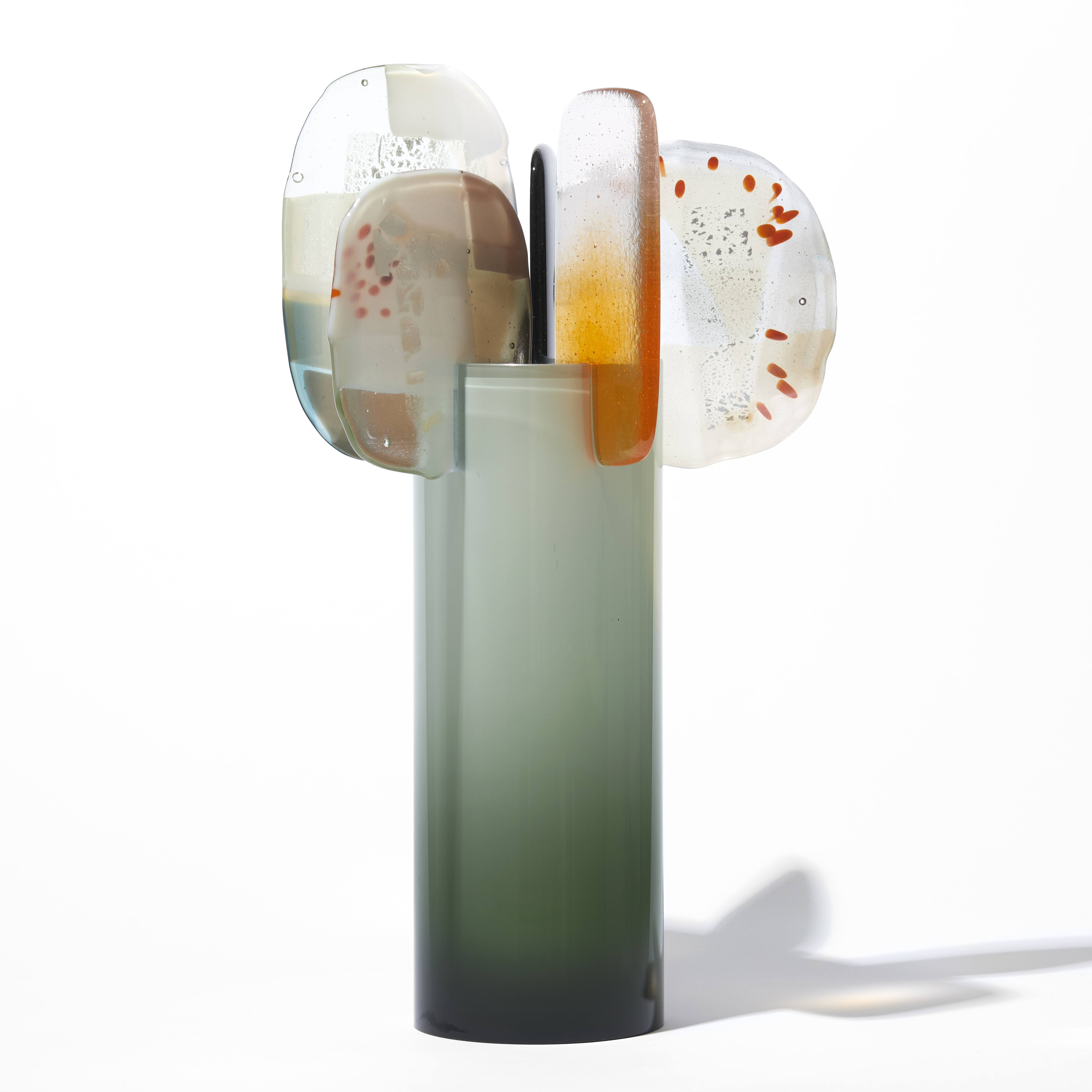 rich green grey cylinder with colour fade towards the top with five rounded abstract finials overlapping the top edge in orange steel opaque white and clear hand made from blown and fused glass