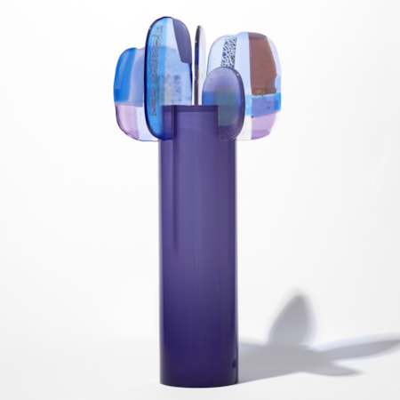 opaque purple cylinder with five simplified petals perched with abstract patterns on the top rim in blue lilac grey and brown hand made from glass
