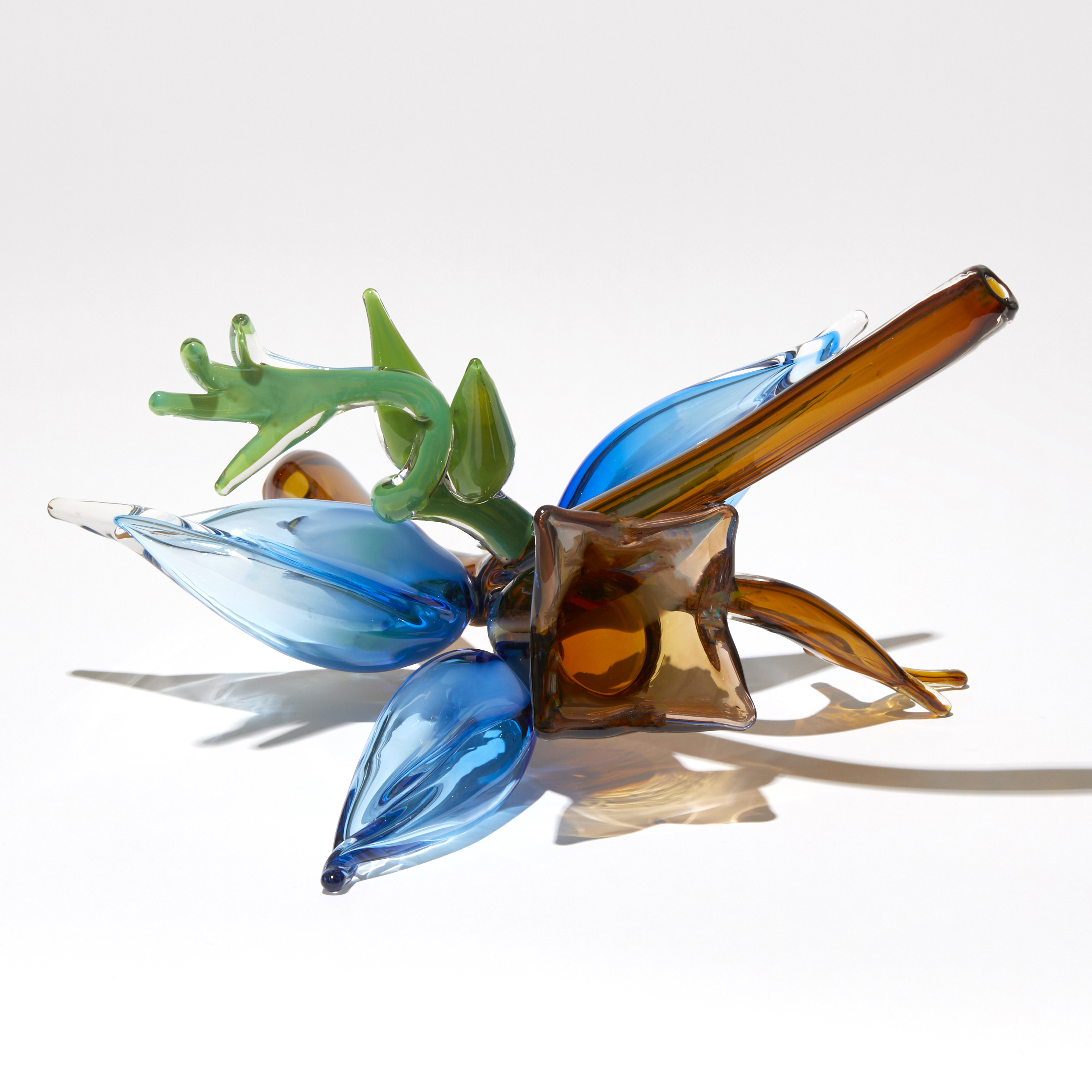 abstract plant inspired sculpture with transparent tobacco coloured stem with a cluster of bright blue buds brown bell shaped flower and bright green tendrils hand made from glass
