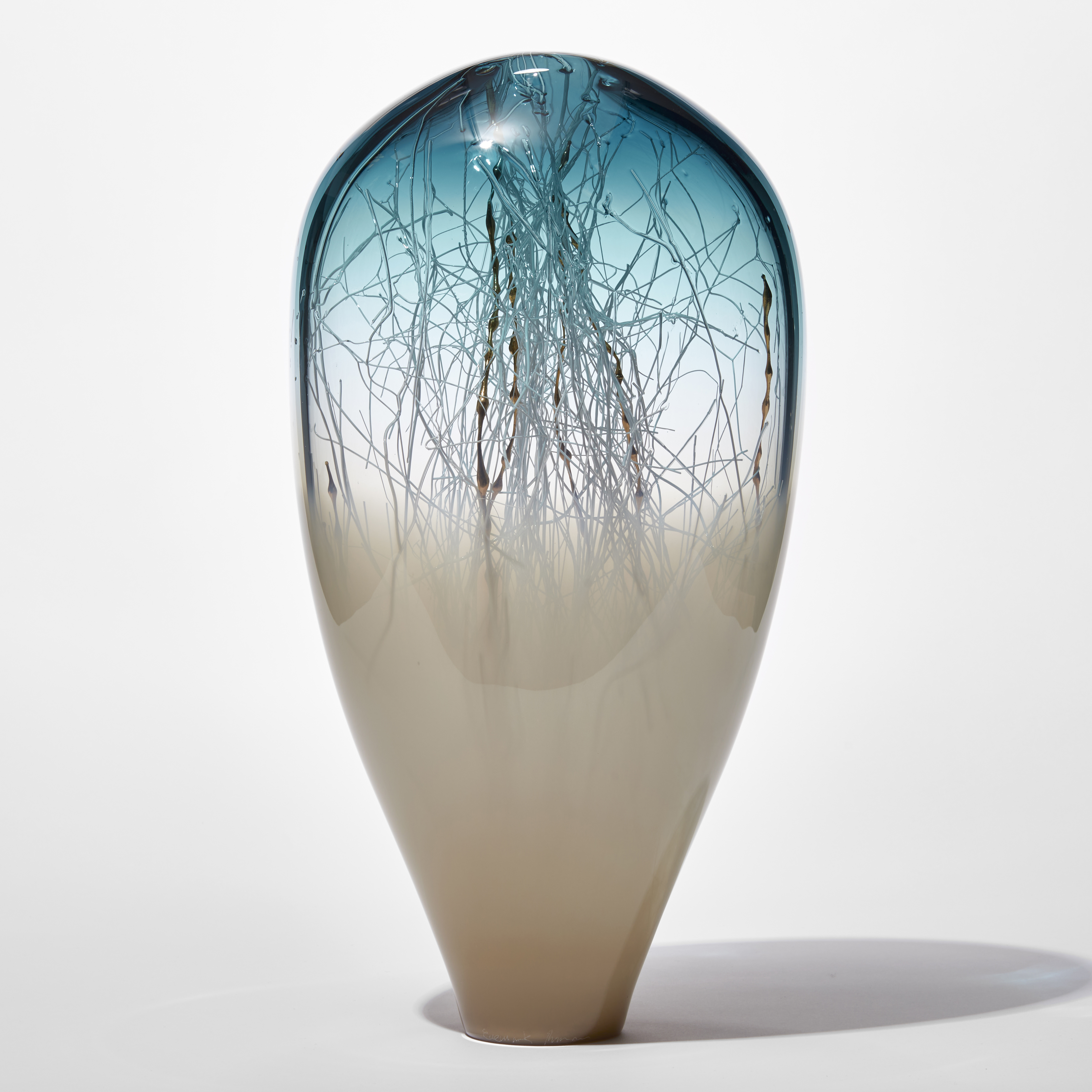 tall transparent and opaque glass sculpture with round top in soft light bronze base and rich blue with fine white canes traversing and trapped inside mixed with gold ones