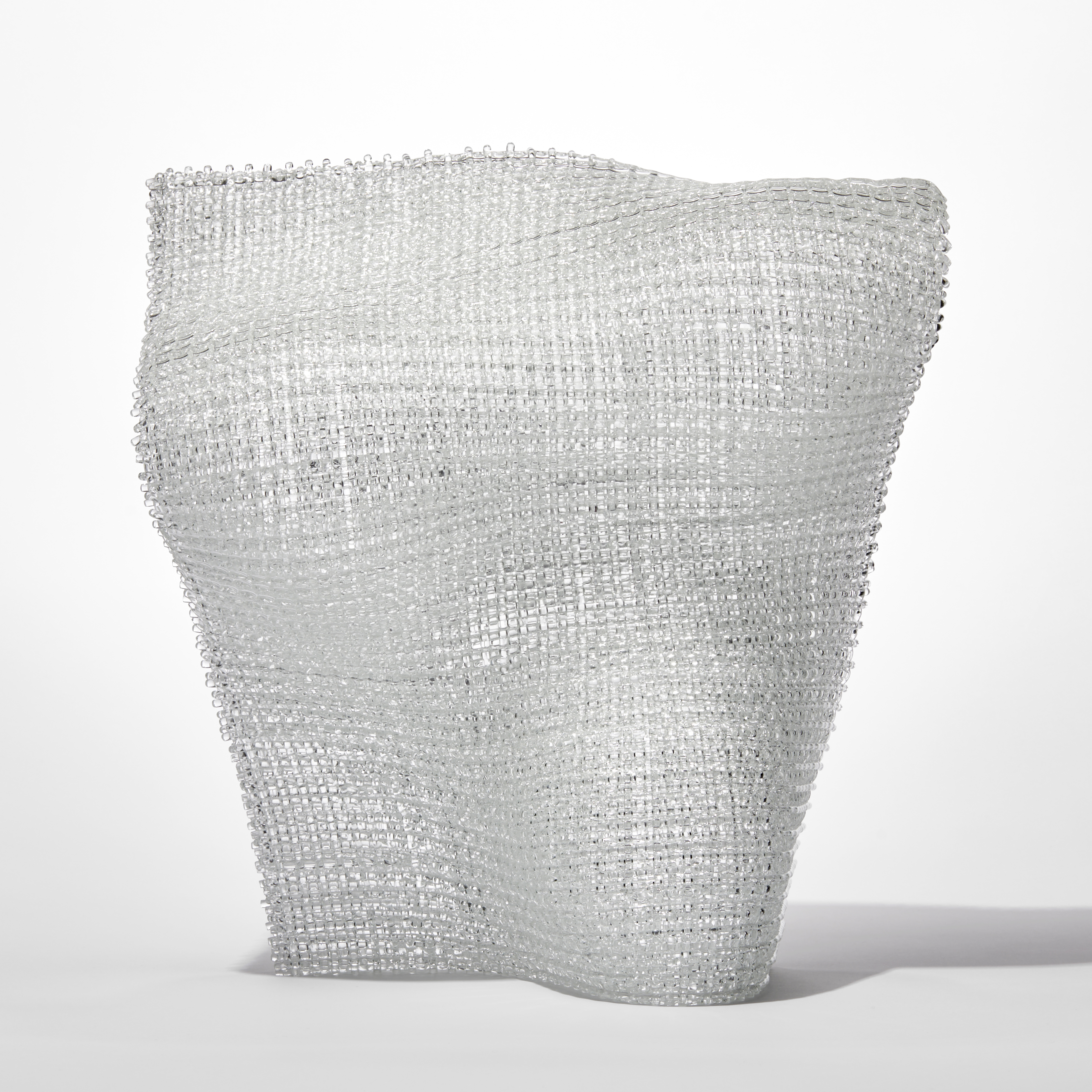 standing undulating clear woven glass sculpture with the appearance for textiles made from layered and fused thin canes of glass