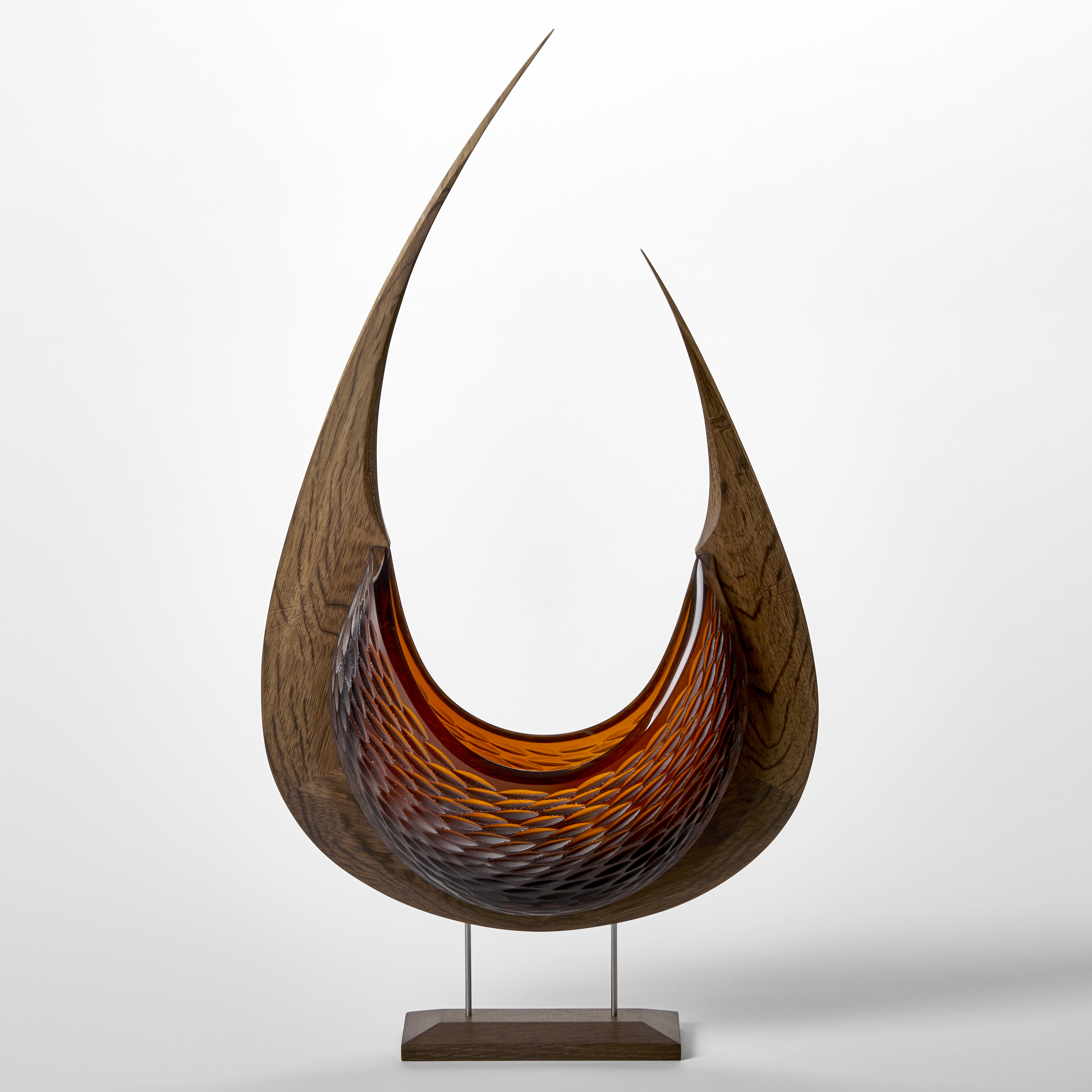 stylised viking ship with curved oak hull and two sections of rich dark amber textured hand blown glass held aloft on a stainless steel and wood base 