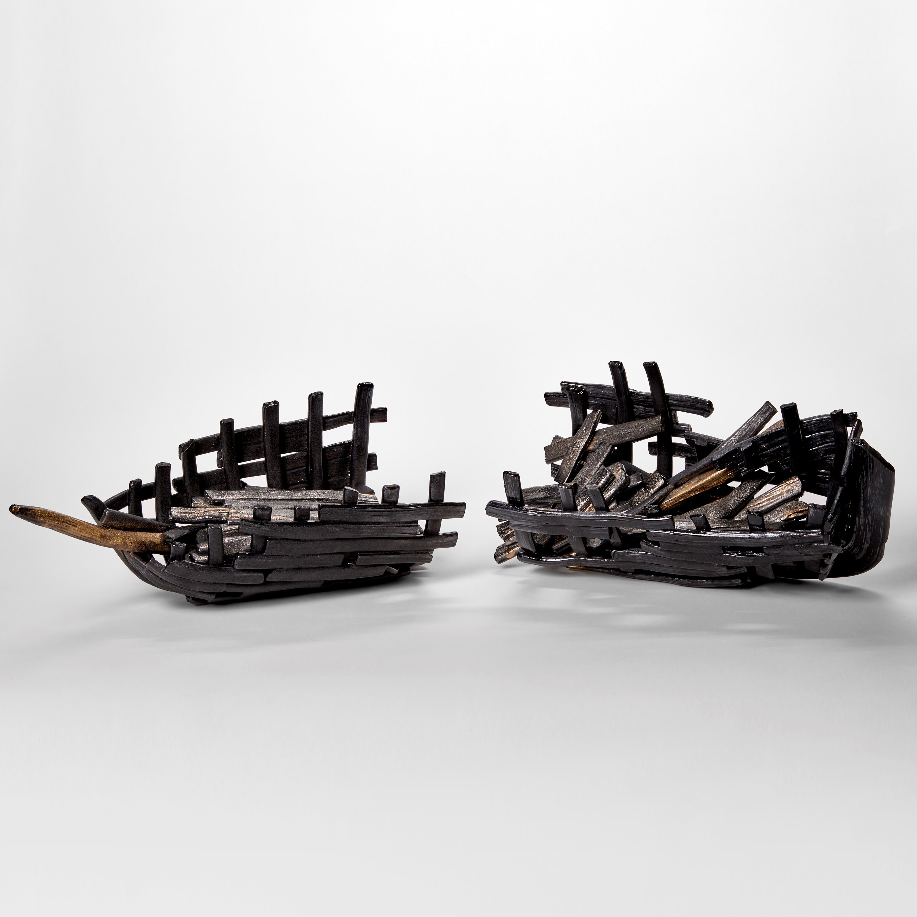 black and bronze hued glass sculpture resembling two halves of a sunken aged ship wreck with split hull and old sea worn timbers