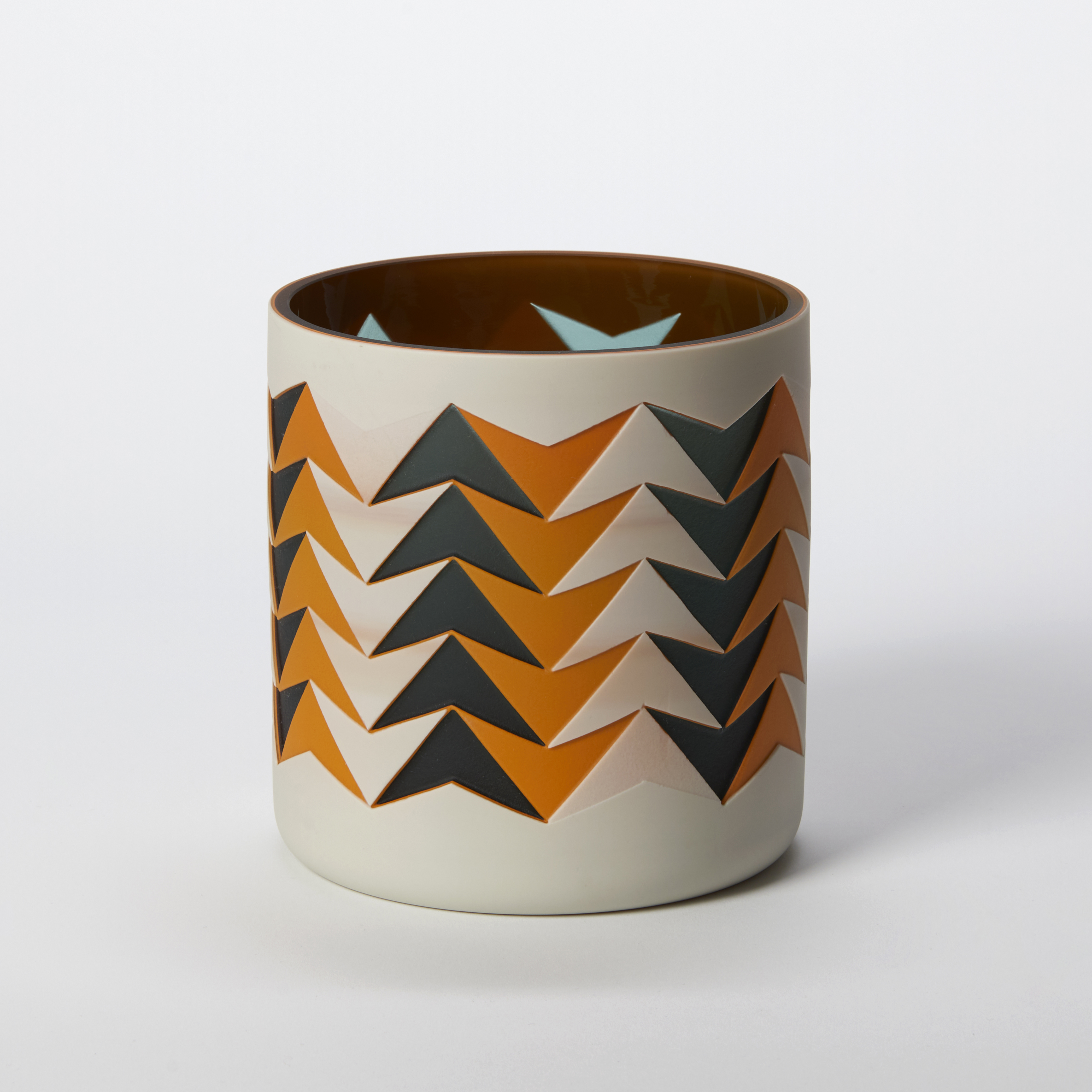 short tubular vase with a geometric pattern of repeat intersected arrows in opaque orange black and beige with a glossy interior hand made from glass