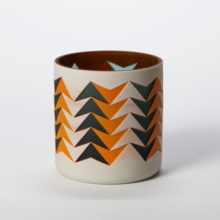short tubular vase with a geometric pattern of repeat intersected arrows in opaque orange black and beige with a glossy interior hand made from glass