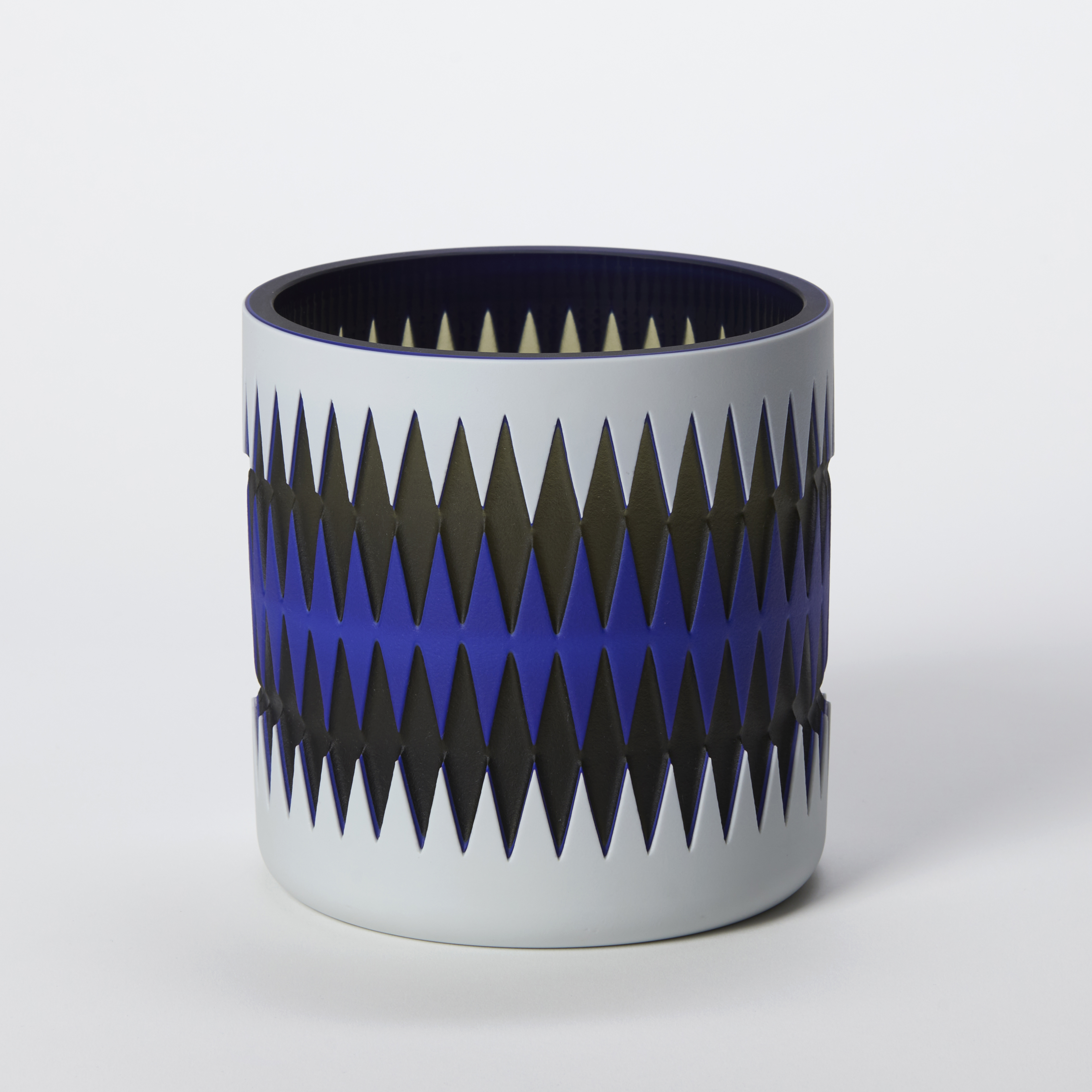 squat low tubular vessel in opaque light grey cobalt blue and black with an external geometric diamond pattern repeated around the form with a glossy interior hand made and blown from glass