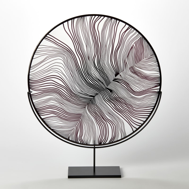 clear and black glass plate with close-up feather cut detail on the surface hand made from glass and presented on a matt black steel stand