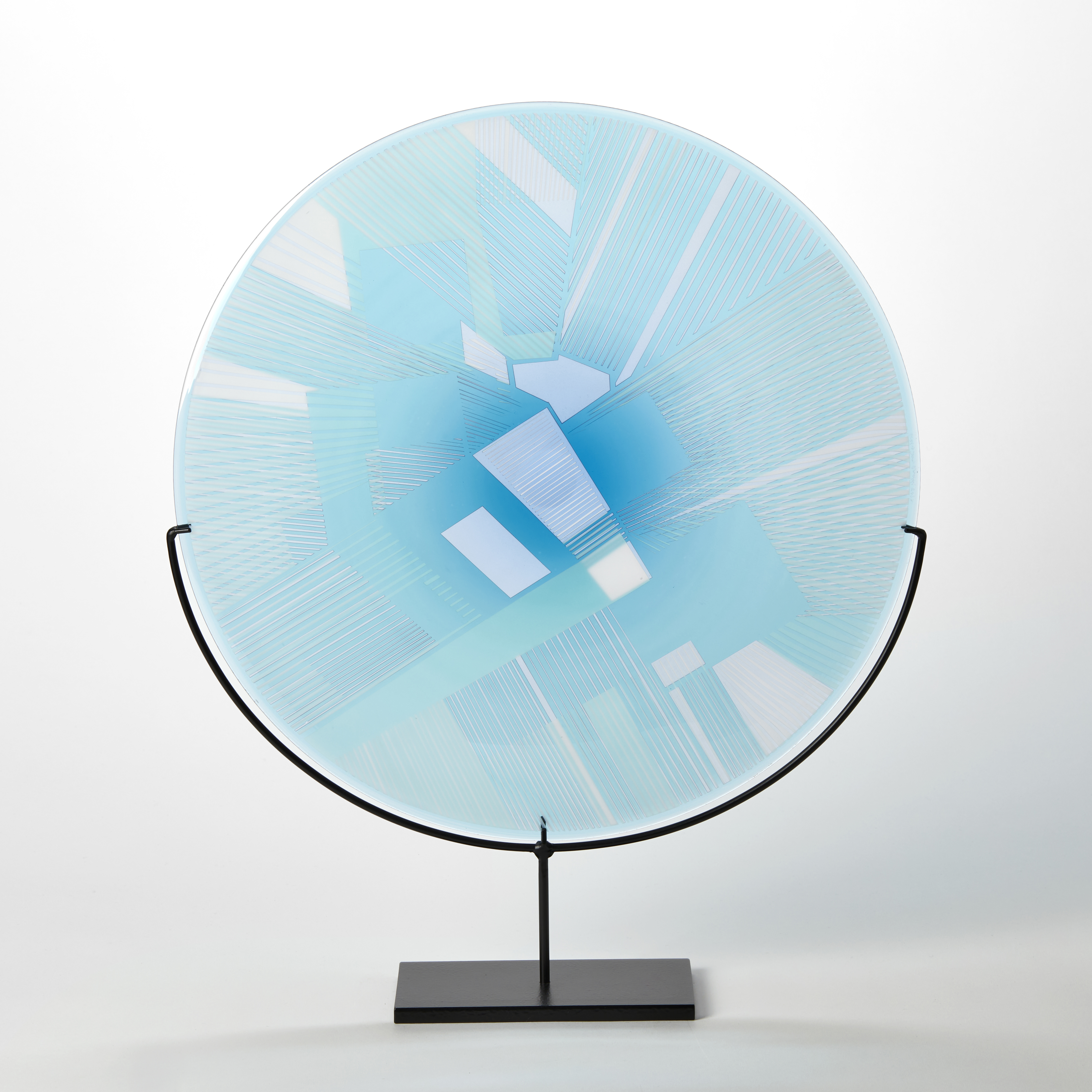 turquoise and blue etched glass plate with raised graphic abstract pattern on a black metal base