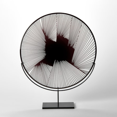 round clear and black hand blown glass decorative plate with abstract linear geometric etched lined pattern on the surface presented on a black steel stand