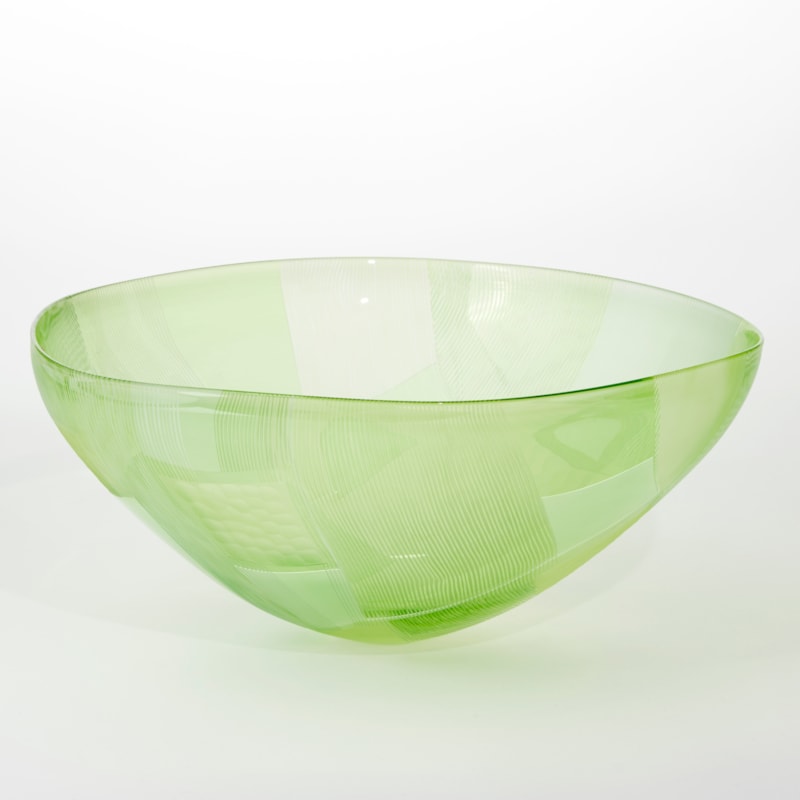 vibrant handblown round bowl with small foot and sweeping wide opening rim with both surfaces covered in abstract cut landscape inspired patterns
