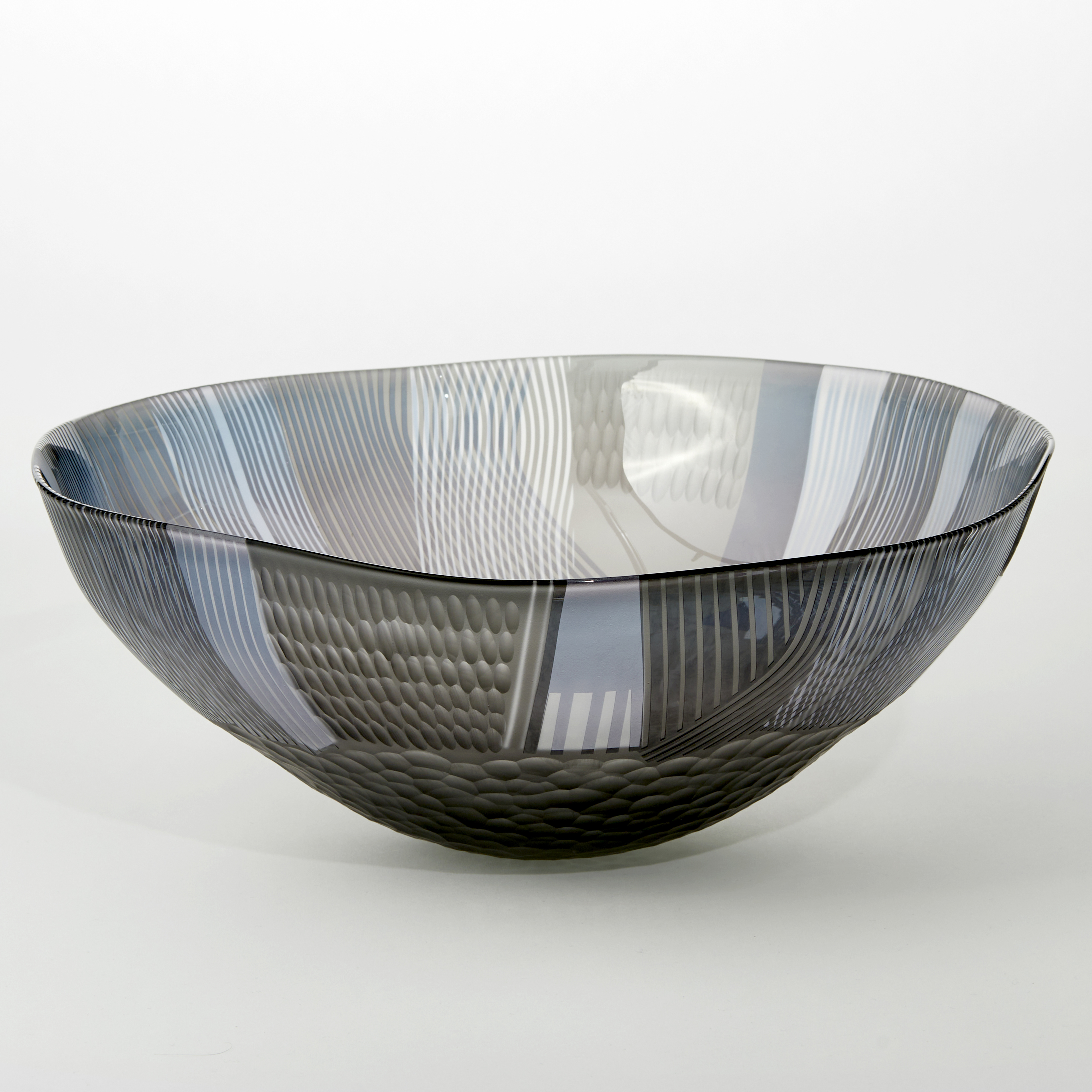 round shallow translucent grey and steel blue bowl with small foot and covered in abstract landscape inspired patterns handblown from glass