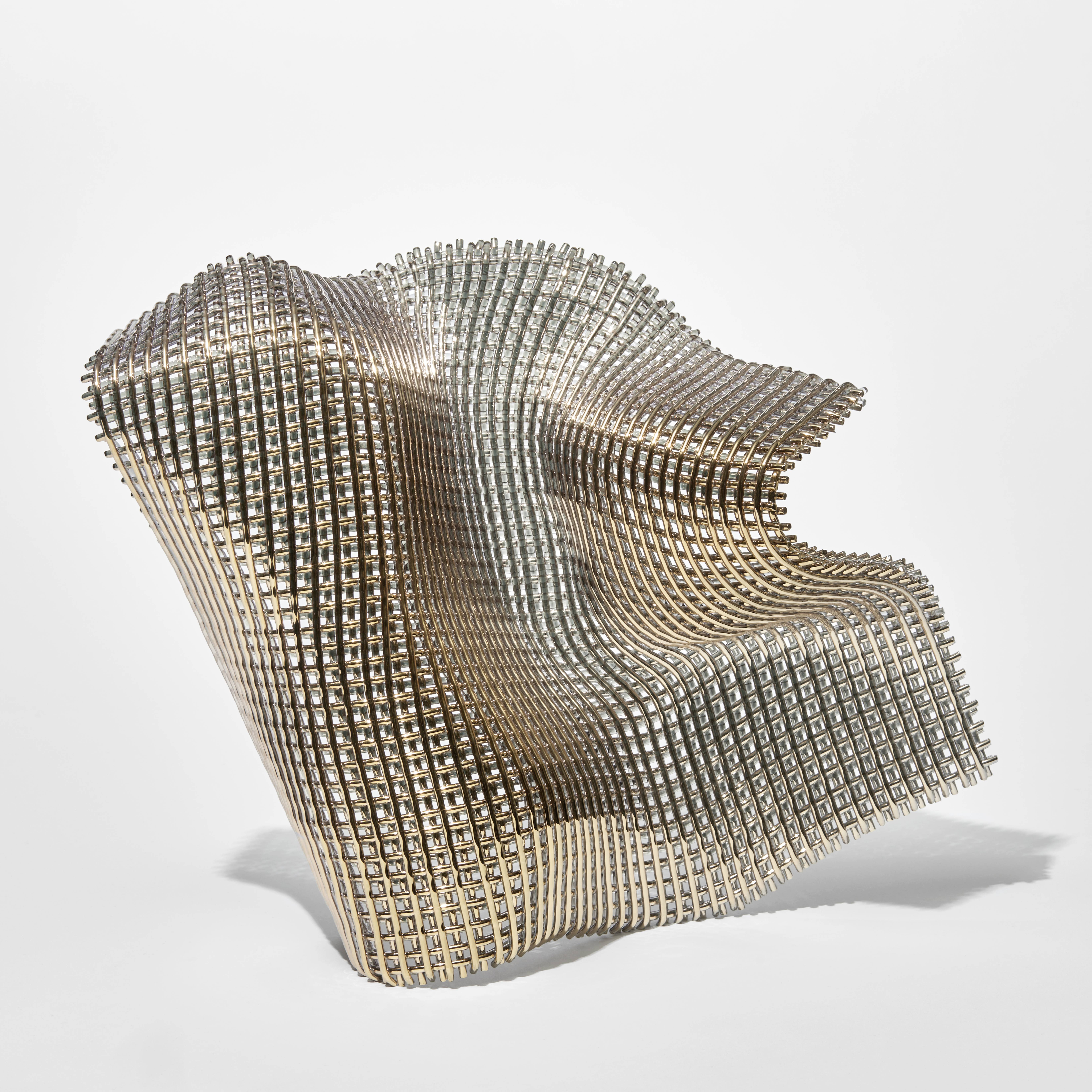 large open woven standing form with the appearance of a fluttering piece of fabric about to hit the ground with the front face covered in gold 