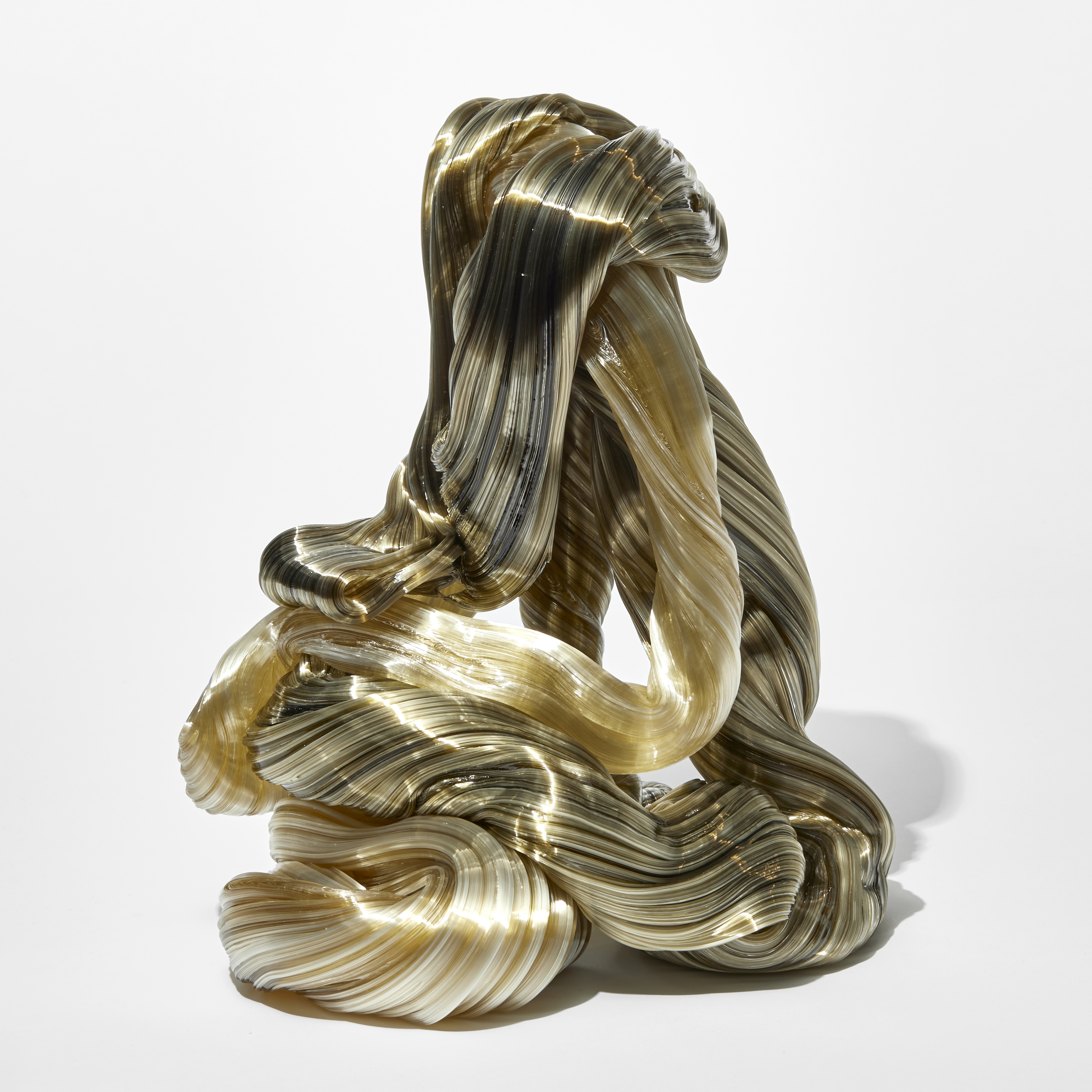 stacked heavy mass of olive green and soft amber thick rope like lengths entwined and looping whilst raising upwards with fine ridges surfaces hand made from glass