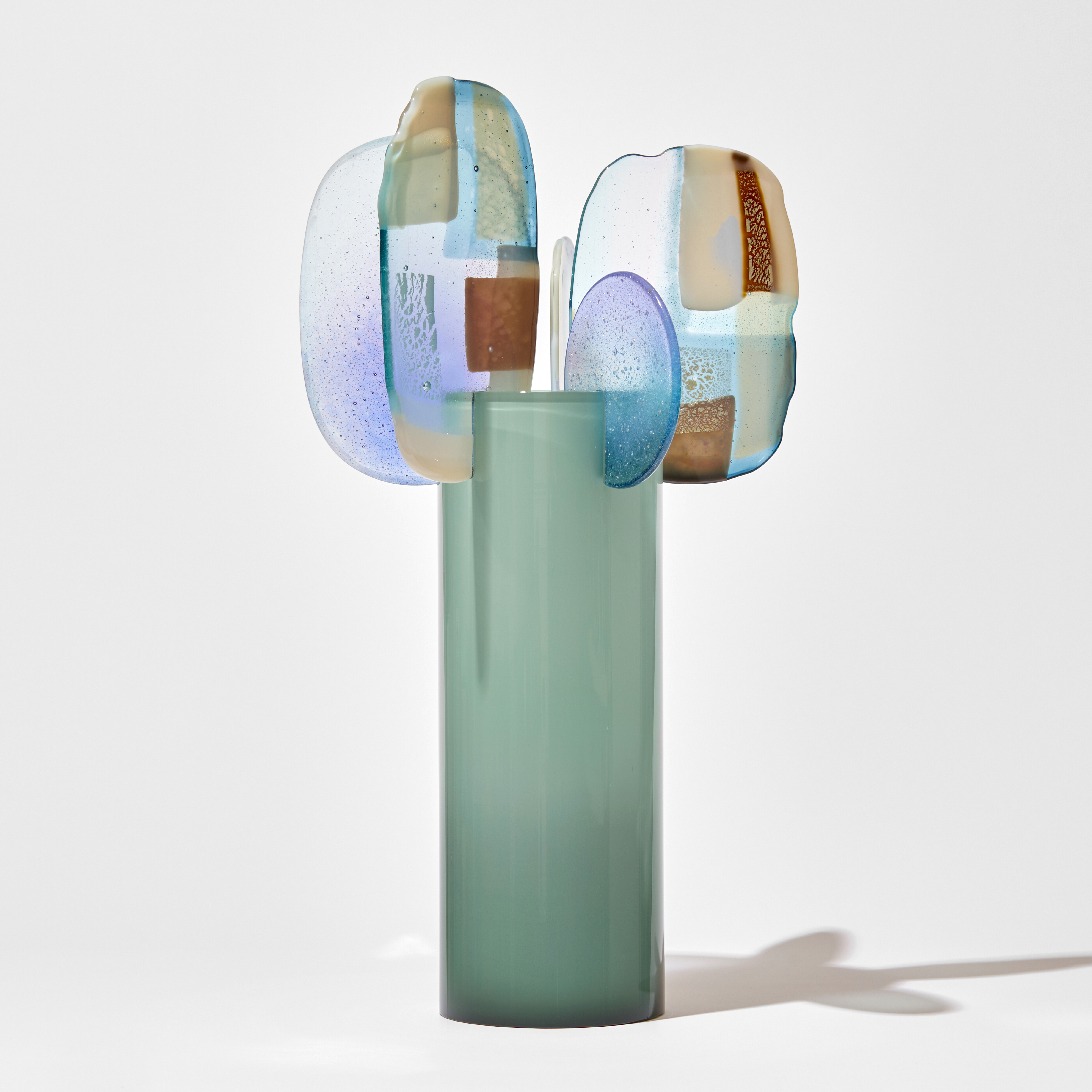 opaque soft celadon tall tube with five different shaped finials perched on the top edge spaced around the perimeter each with abstract patches of colour in lilac jade bronze and cream hand made from glass