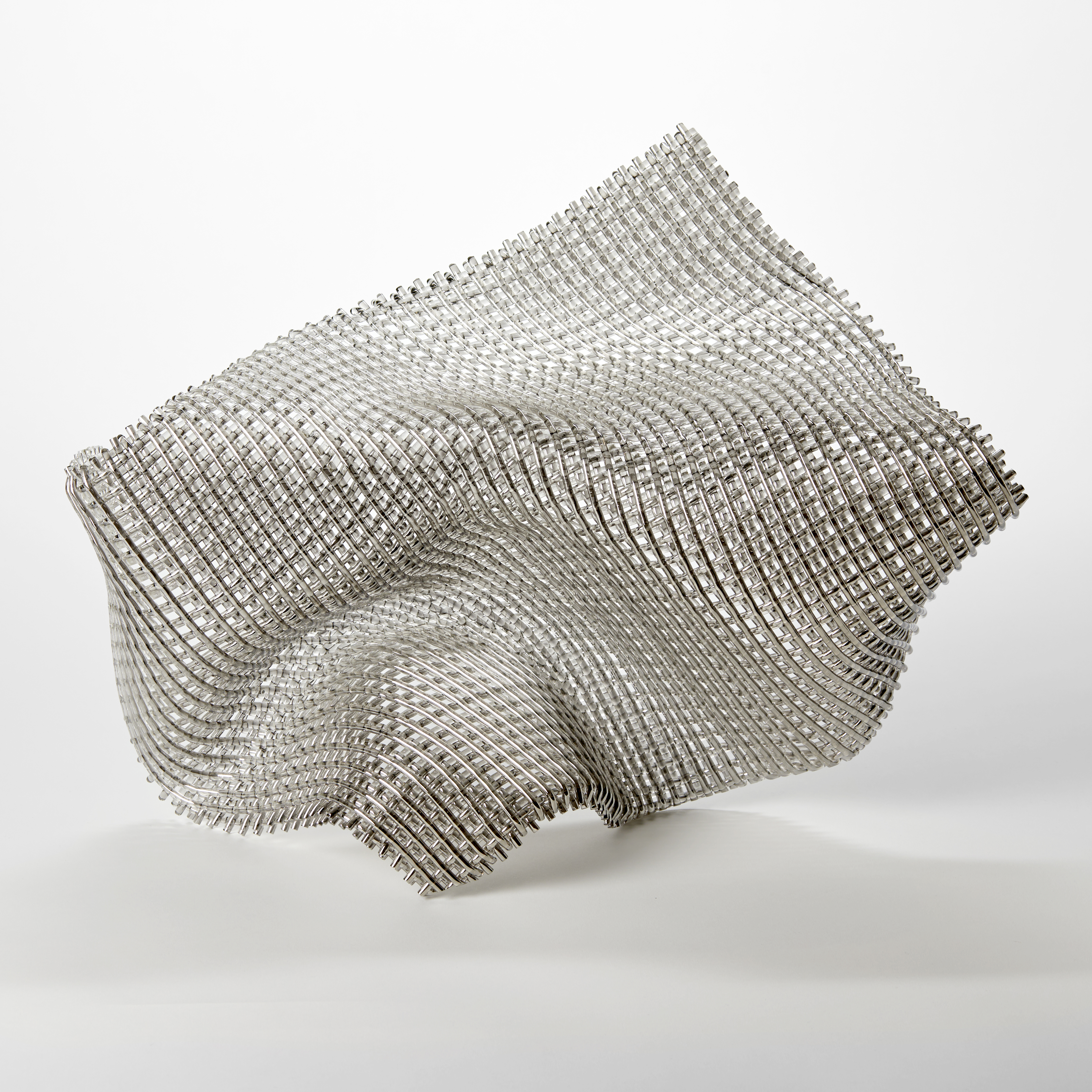 collapsing glass abstract sculpture with the appearance of falling fabric with a very open weave and front face covered in silver