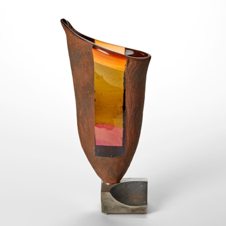 flaring rust coloured sculptural vessel with lifting rim with slanting top and two transparent windows in orange peach and ochre glass perched on a heavy large steel base
