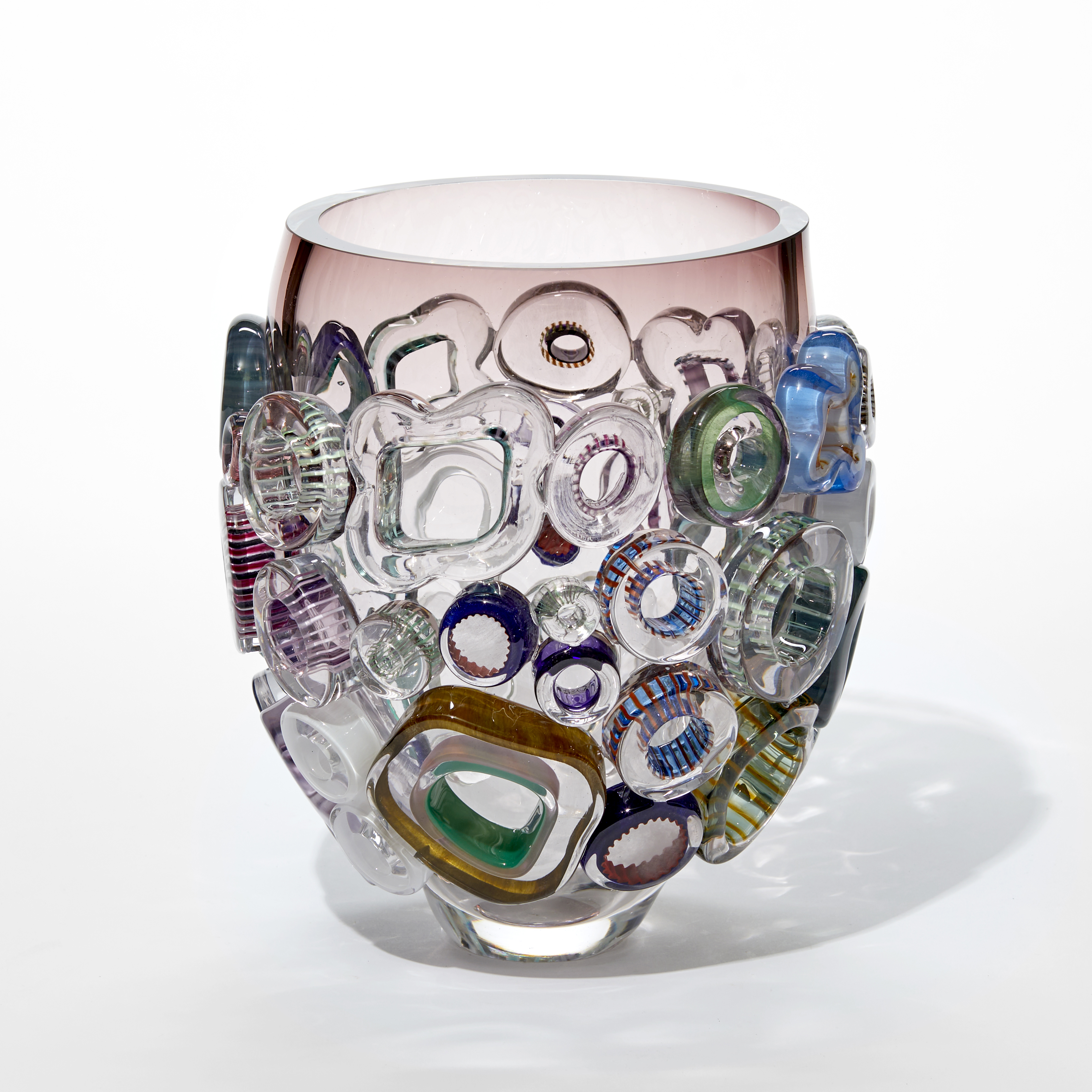 transparent aubergine brown and clear vase with flared shape covered in chubby flat patterned rings in blue green jade and pink hand made from glass