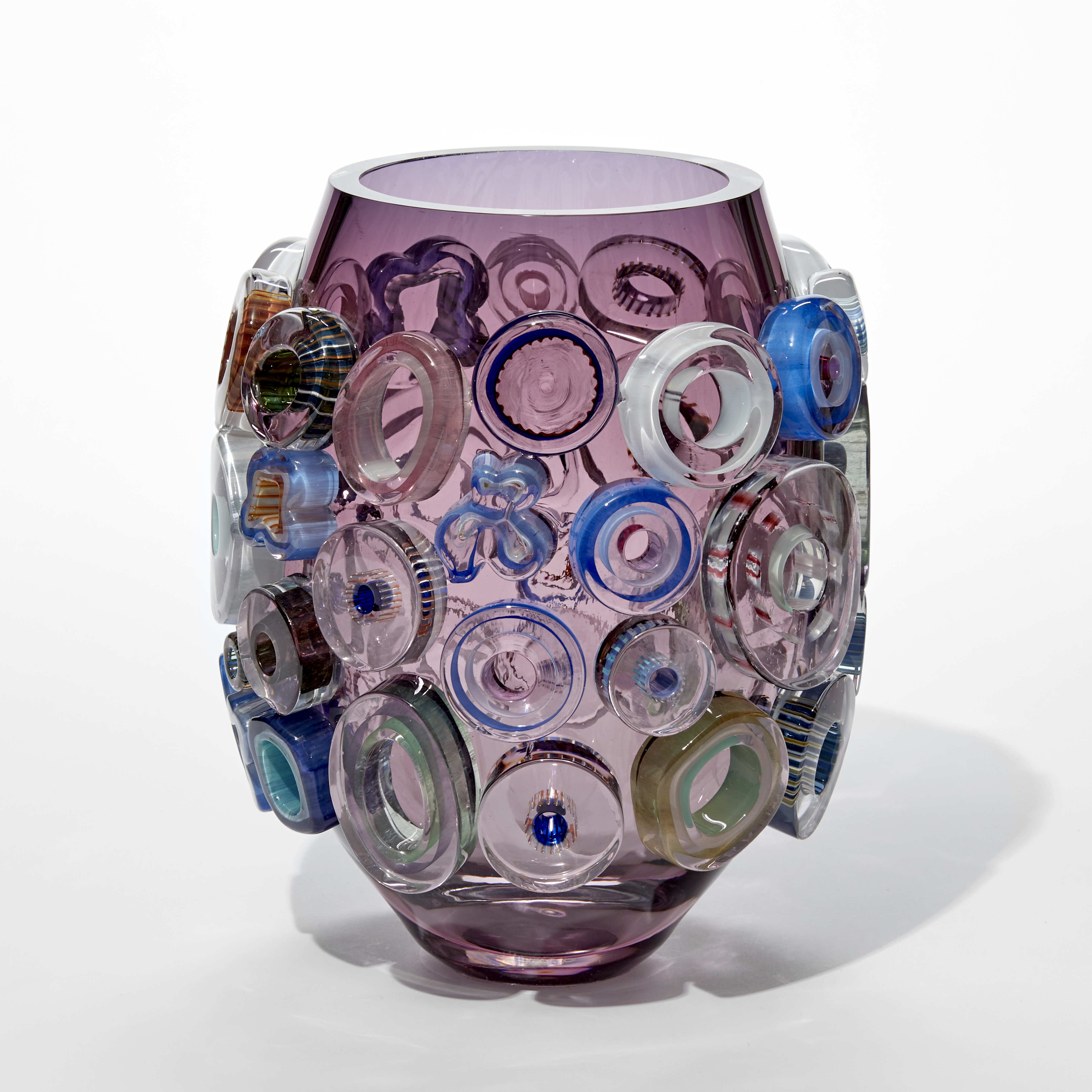 transparent aubergine and purple short barrel shaped vase with surface decoration of raised chubby flat rings in pink celadon blue and pink hand made from glass