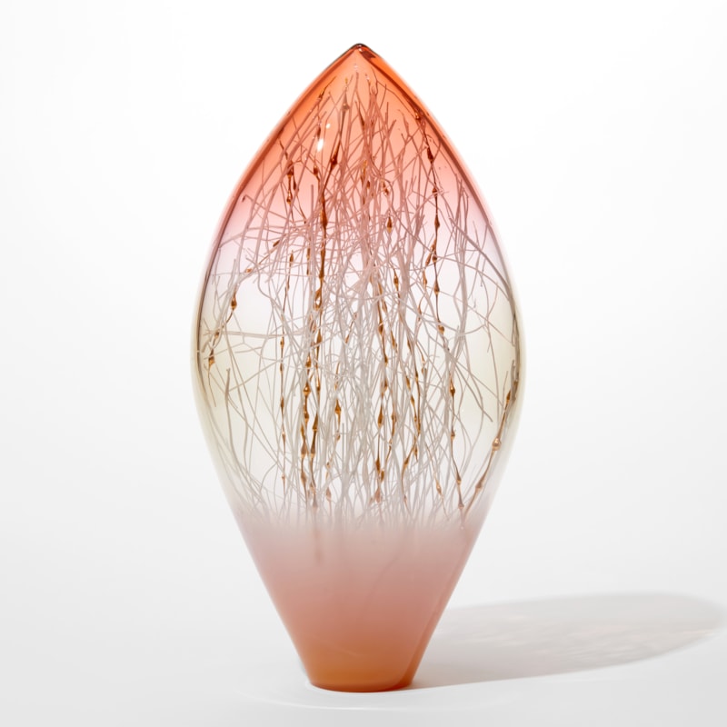 transparent artwork in a tear shape with pointed top opaque pink bottom half fading to clear then fading to transparent peachy pink at the top with fine canes in white and gold with bobbles filling the interior space