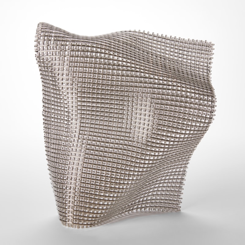 standing silvery shimmering form with the appearance of fabric with folds and subtle undulations hand made from fused glass and nickel chromium
