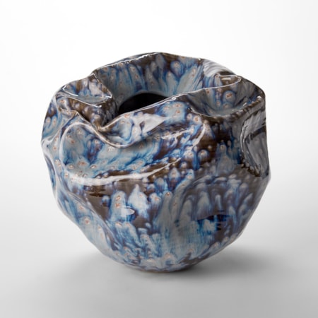 round crumpled and creased vase with crevasse top opening and blue and brown running glazed surface hand thrown from white saint thomas clay