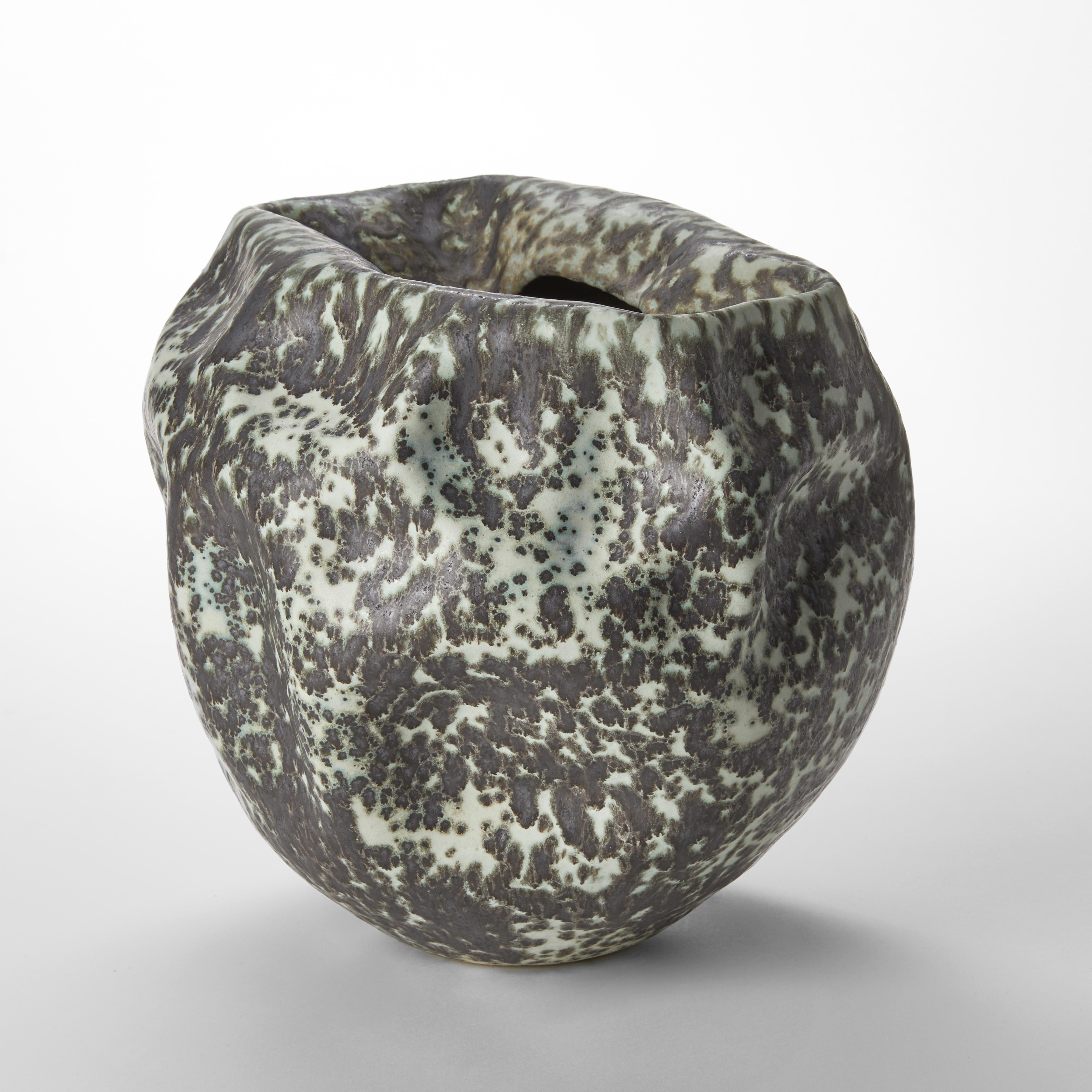 mint green stone like organic vessel with soft crumples and creases and top central crevasse opening with merging iron brown black patches on the surface hand made from clay