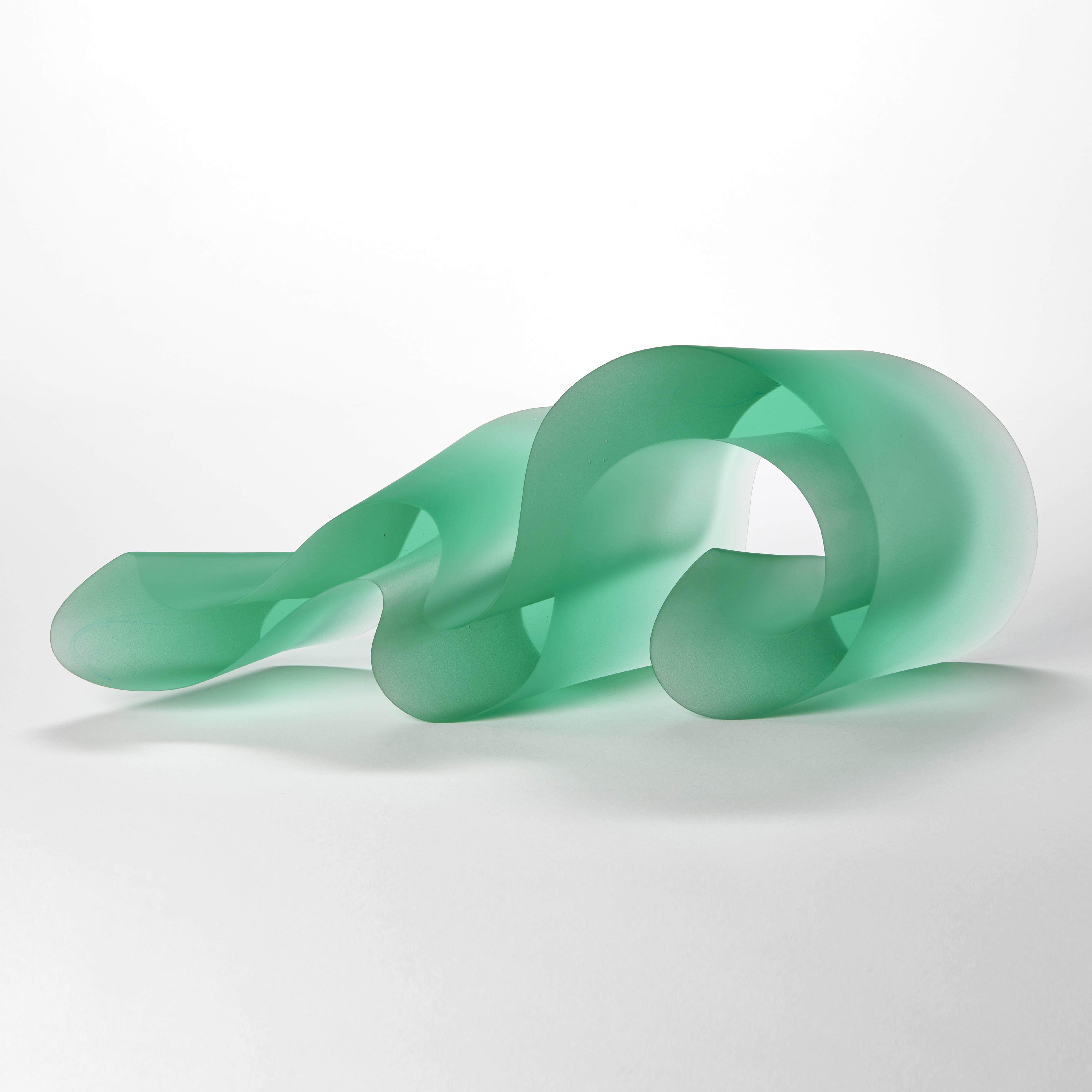 curling undulating bright jade lime green opaque sculpture with two flat sides and two curling sides following the movement of the piece as it waves and snakes along in form hand made from cast glass