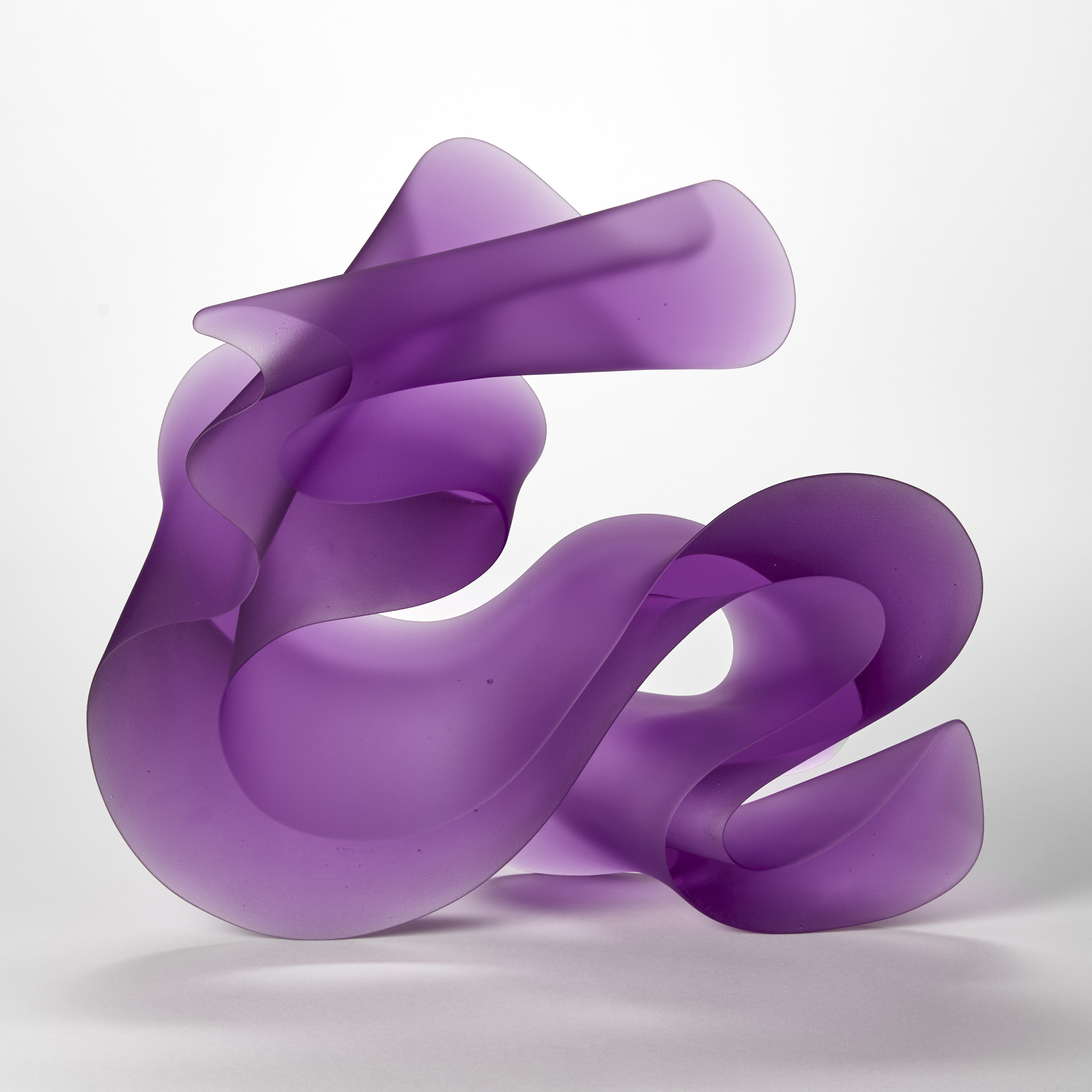 swirling standing opaque cast glass artwork in a brilliant purple lilac colour with the appearance of calligraphy and almost abstract arabic text with two sides shiny flat and parallel and two undulating and curling creating a dramatic outline