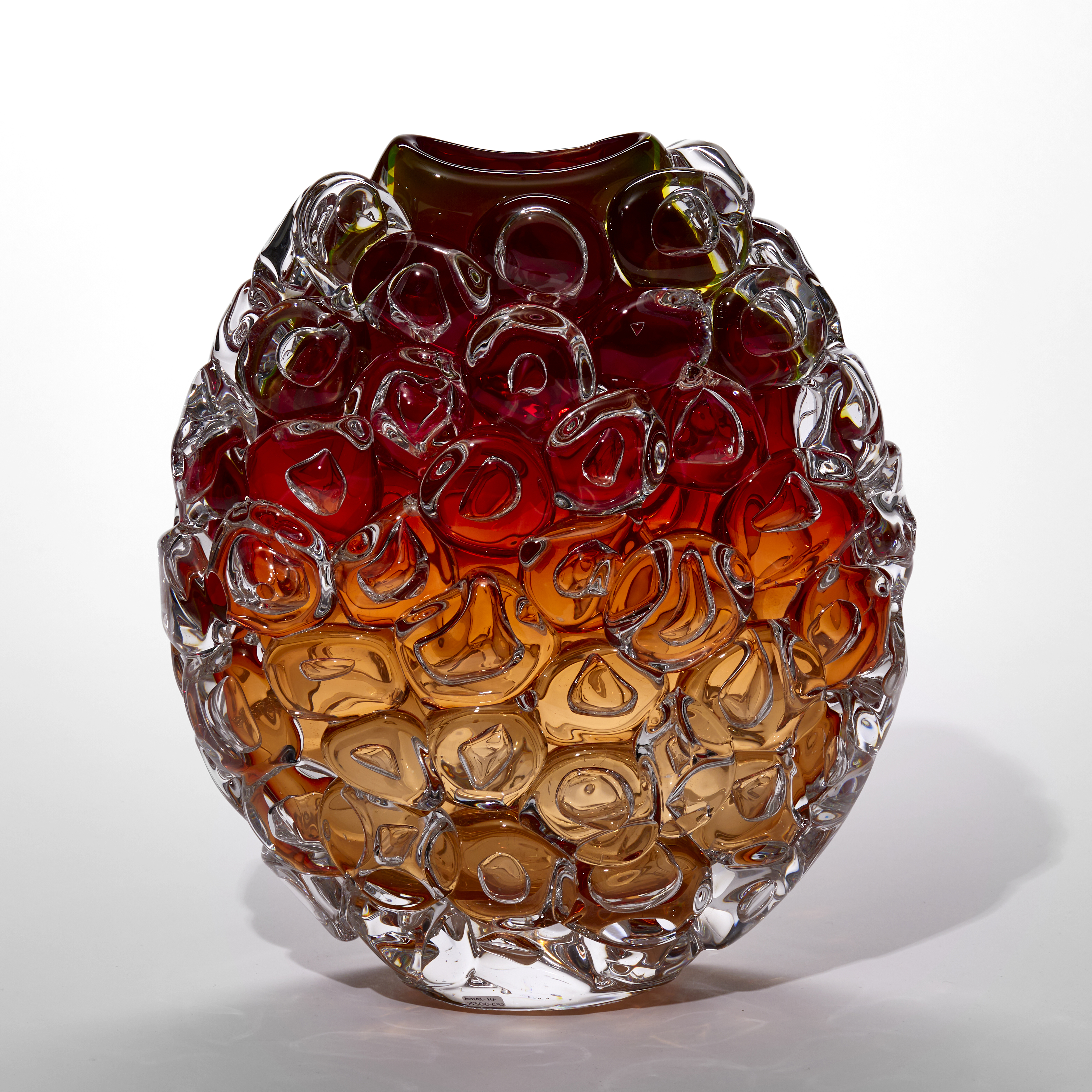 round transparent vase with curved top opening fading from soft peach at the base to ox blood red at the top and covered in oversized bubbles like bubblewrap