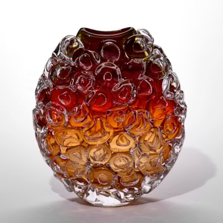 round transparent vase with curved top opening fading from soft peach at the base to ox blood red at the top and covered in oversized bubbles like bubblewrap