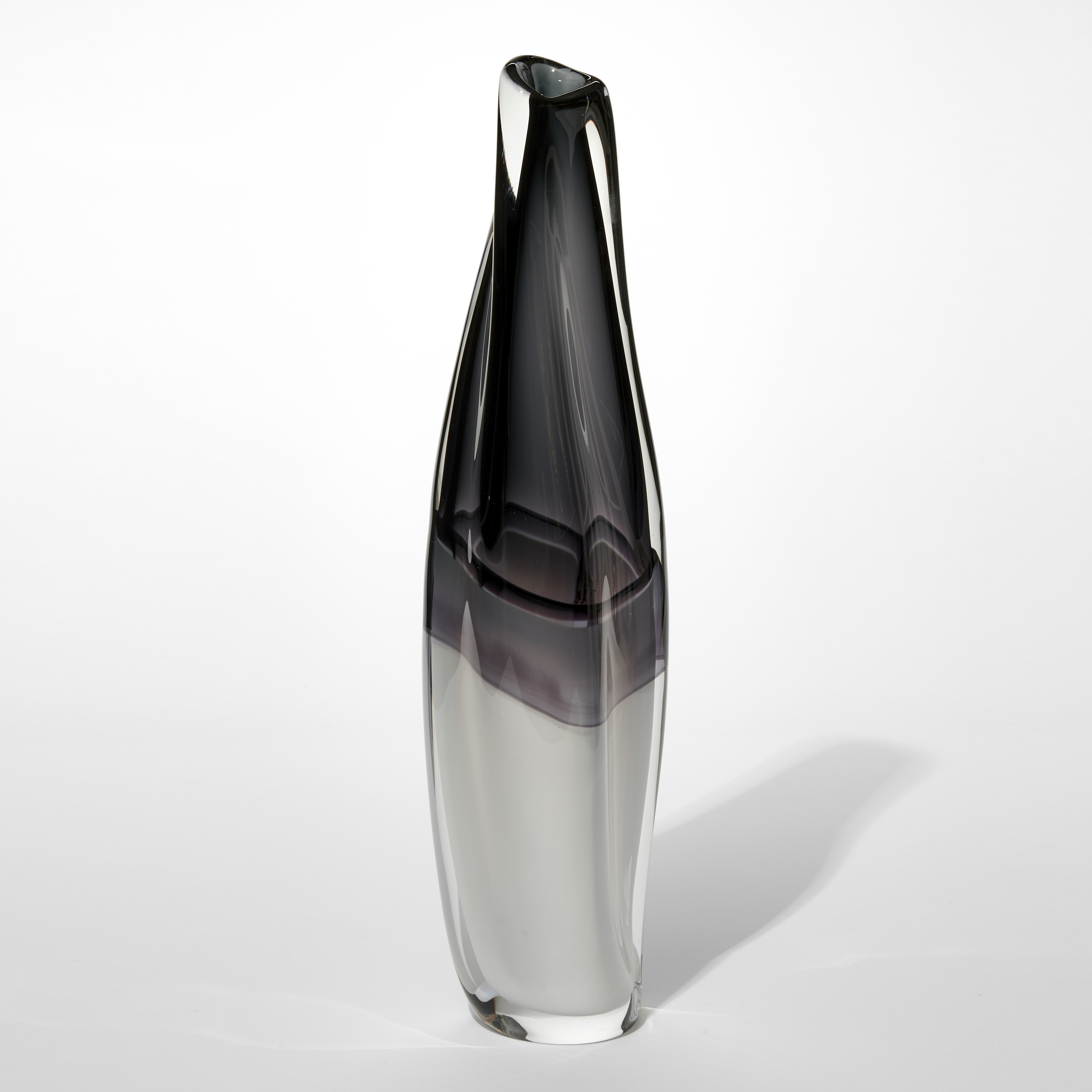 fluid twisting vase with bisected monochrome colouring with the bottom opaque white merging to smokey grey black at the top hand made from glass